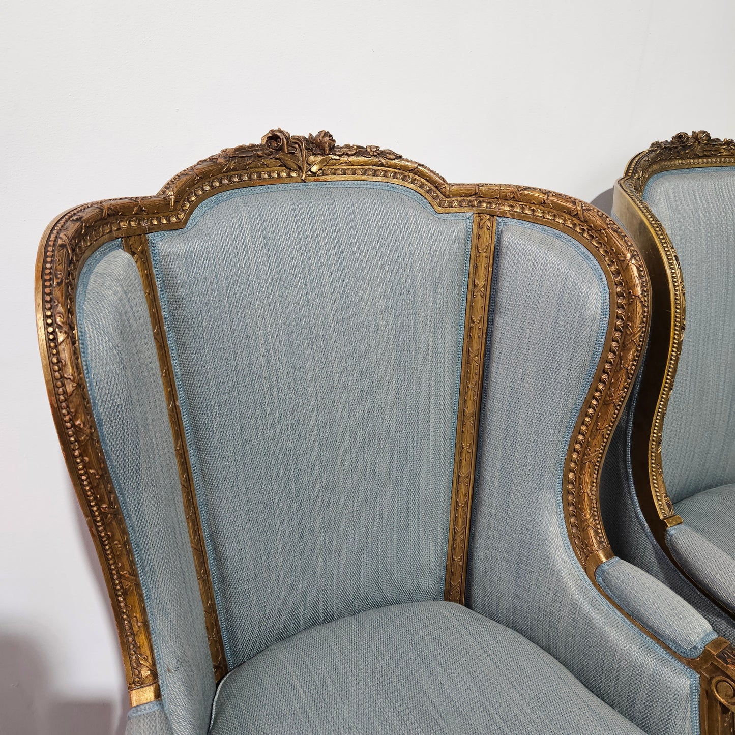 Lovely pair of Louis 16th style gilt & upholstered wingback bergeres with two comfortable cushions. These chairs are in good original condition. Please view photos as they form part of the description.