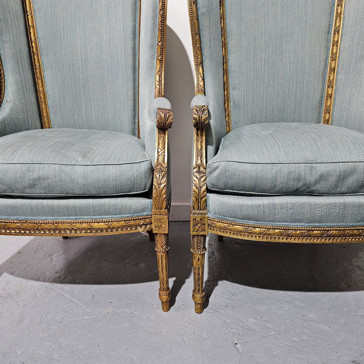Lovely pair of Louis 16th style gilt & upholstered wingback bergeres with two comfortable cushions. These chairs are in good original condition. Please view photos as they form part of the description.