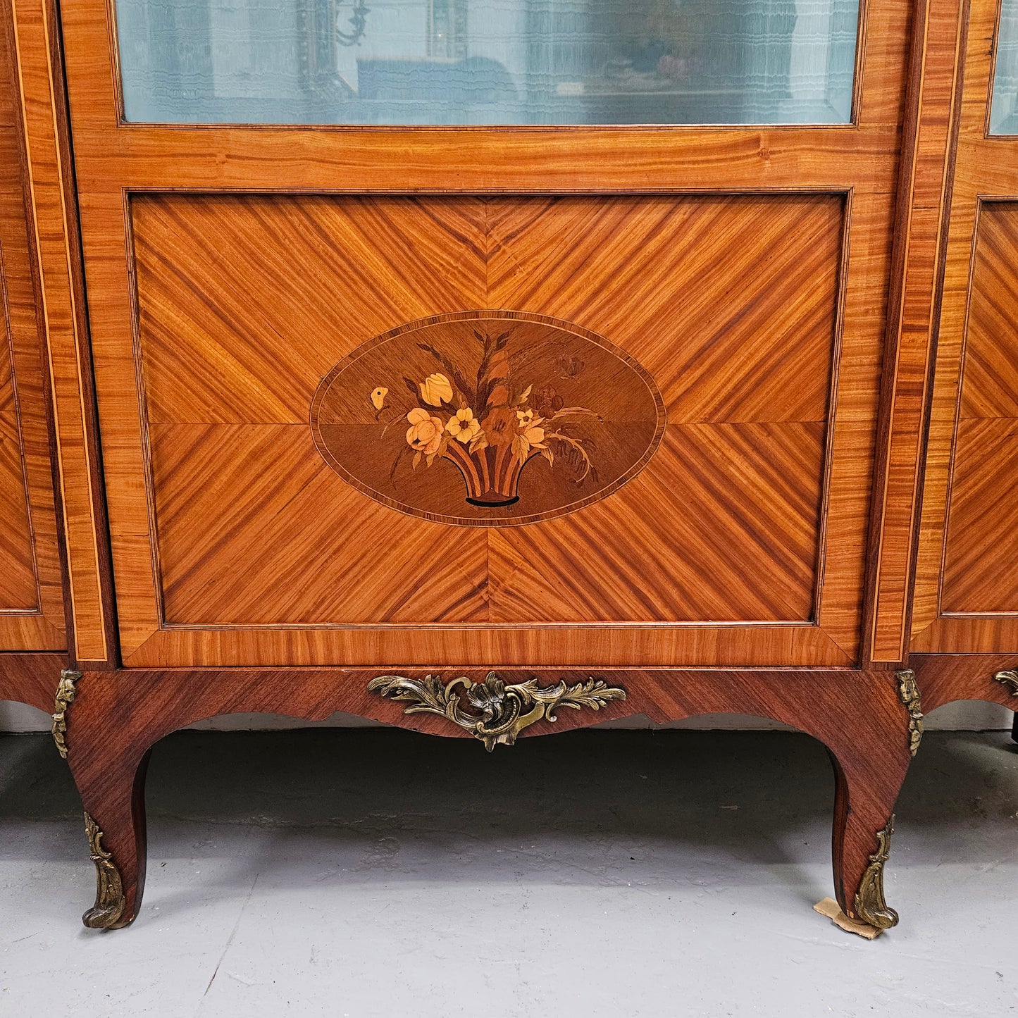 Elegant three door Louis XV transitional style vitrine with decorative bronze mounts. This unit has two glass shelves and one wooden shelf providing plenty of storage. It is in great original detailed condition. Please see the photos as they form part of the description.