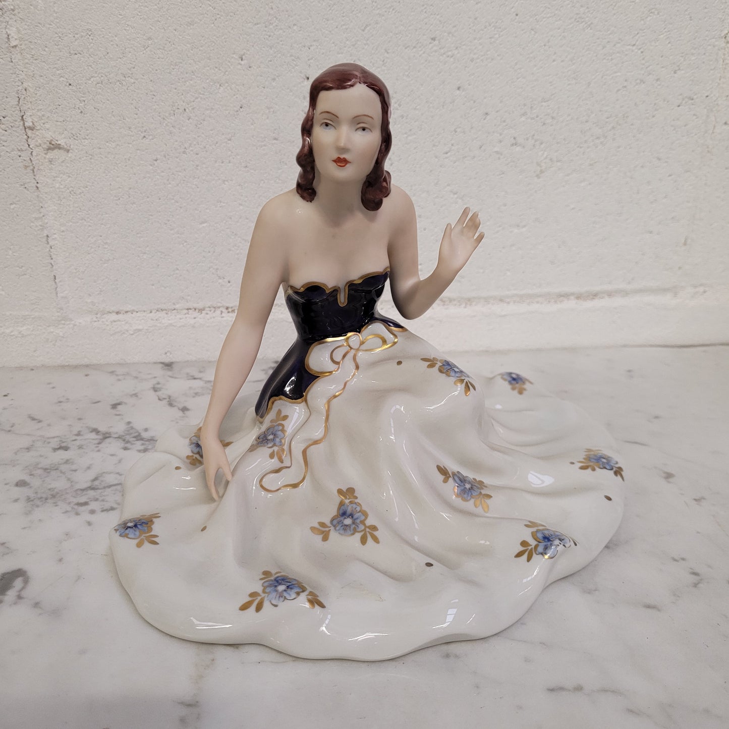 This Royal Dux Bohemia seated figurine of a lady is a beautiful and sophisticated piece. She is wearing a cobalt blue and white dress, and is in good original condition; please review the accompanying photos for more details.