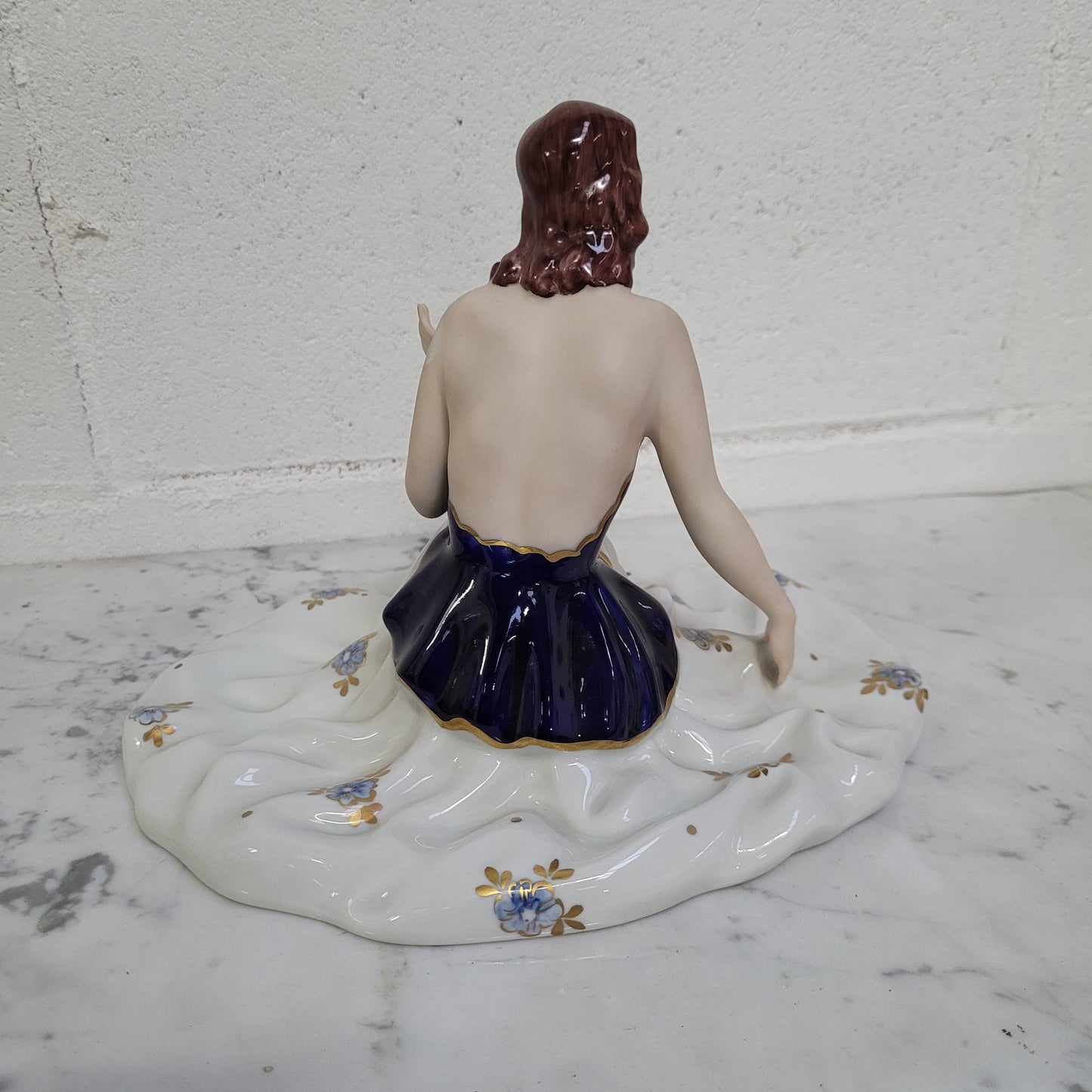 This Royal Dux Bohemia seated figurine of a lady is a beautiful and sophisticated piece. She is wearing a cobalt blue and white dress, and is in good original condition; please review the accompanying photos for more details.