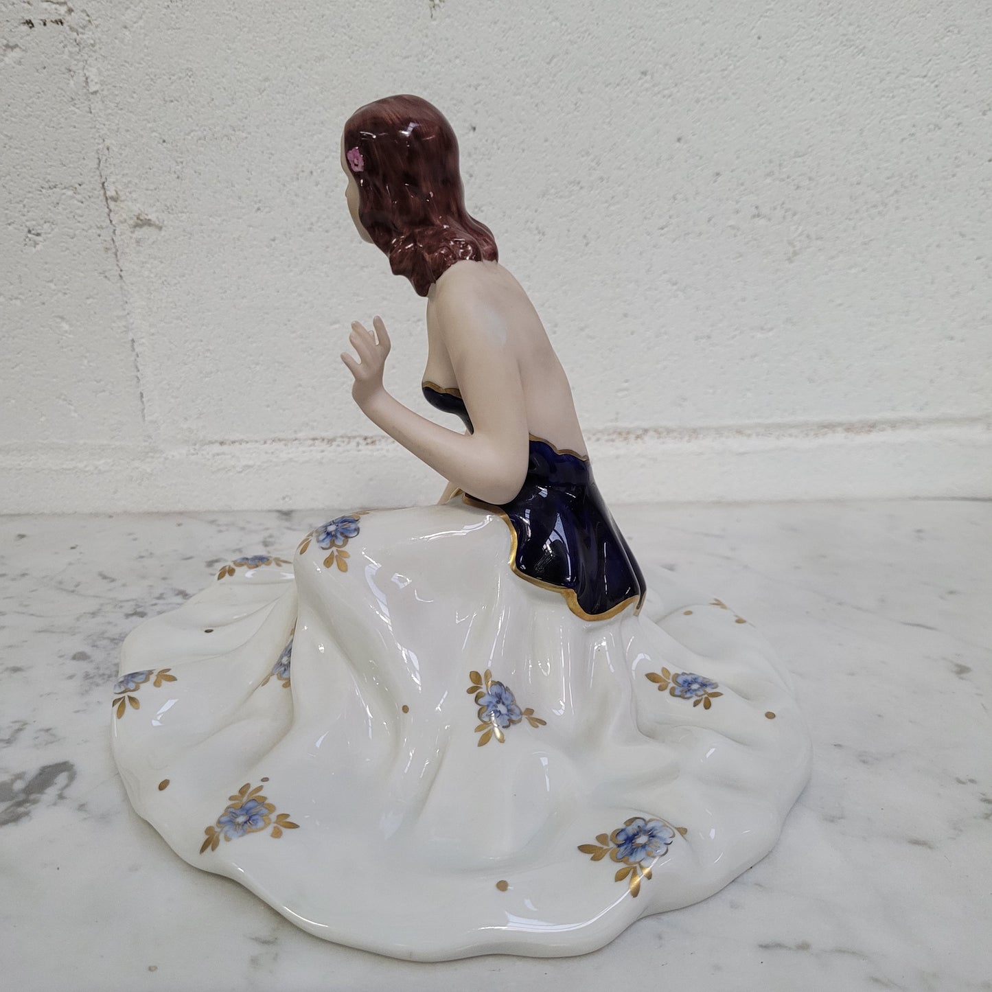 This Royal Dux Bohemia seated figurine of a lady is a beautiful and sophisticated piece. She is wearing a cobalt blue and white dress, and is in good original condition; please review the accompanying photos for more details.