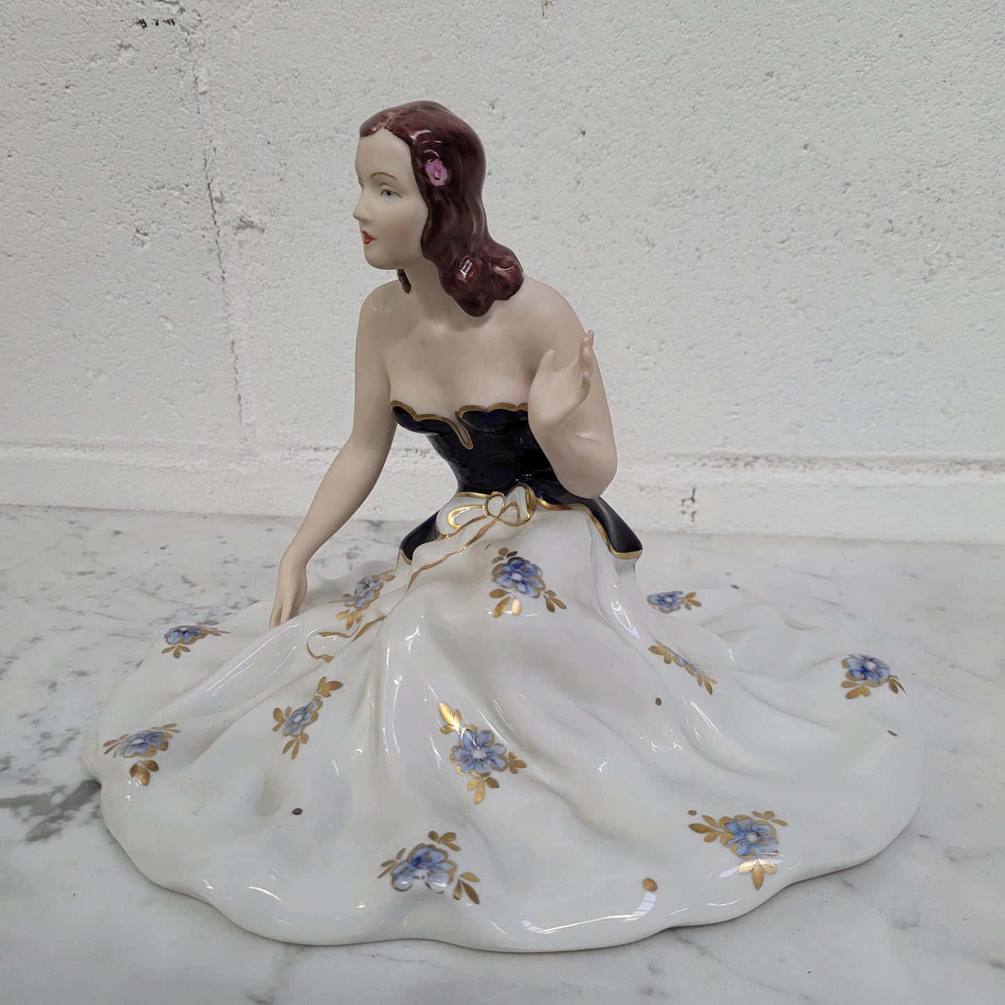 This Royal Dux Bohemia seated figurine of a lady is a beautiful and sophisticated piece. She is wearing a cobalt blue and white dress, and is in good original condition; please review the accompanying photos for more details.