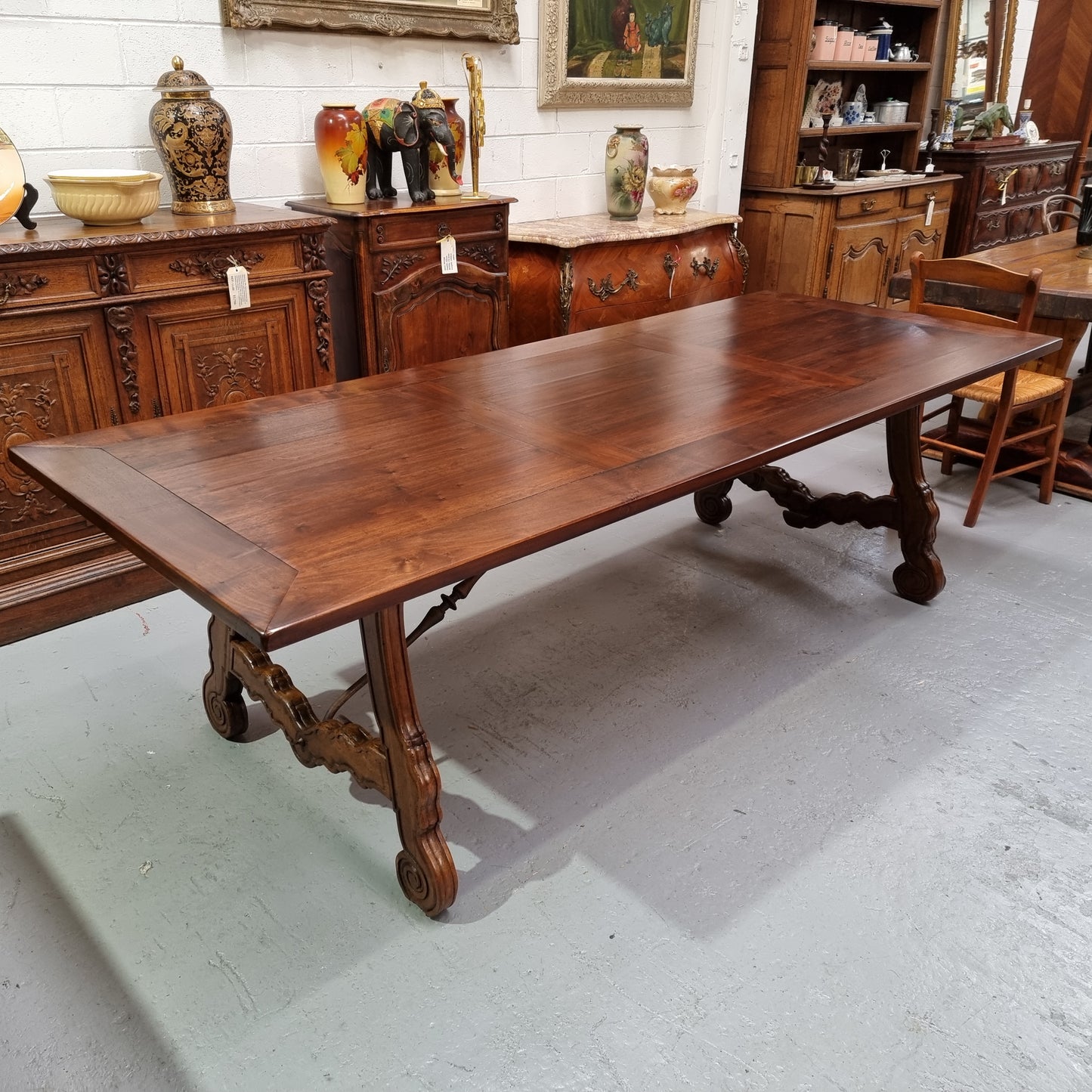 This exquisite 2.5m-long dark oak Spanish style dining table showcases exceptional ironwork underneath and is sourced from France, it is in good original detailed condition