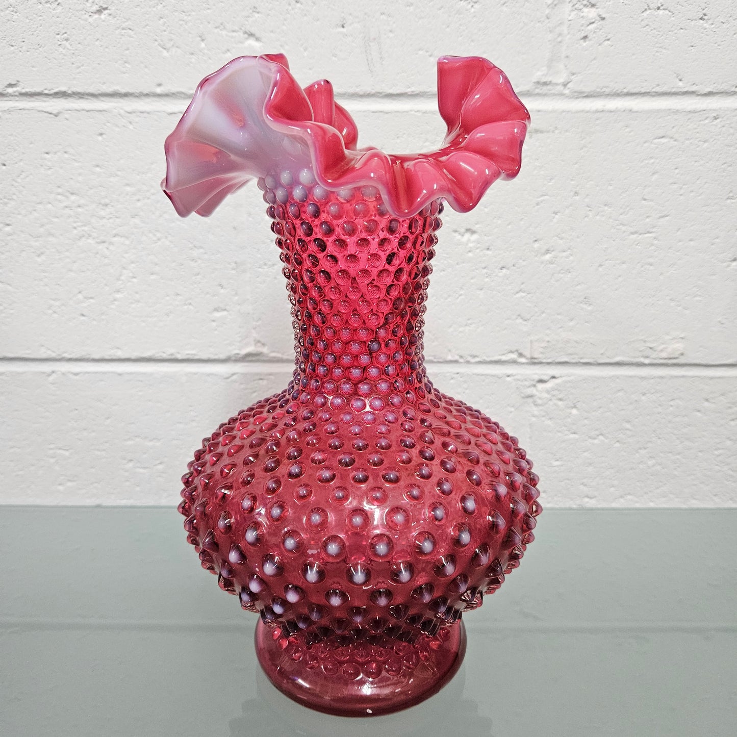 Large vintage Fenton cranberry glass vase with opalescent trim and frilled top. In good condition. Please see photos as they form part of the description.