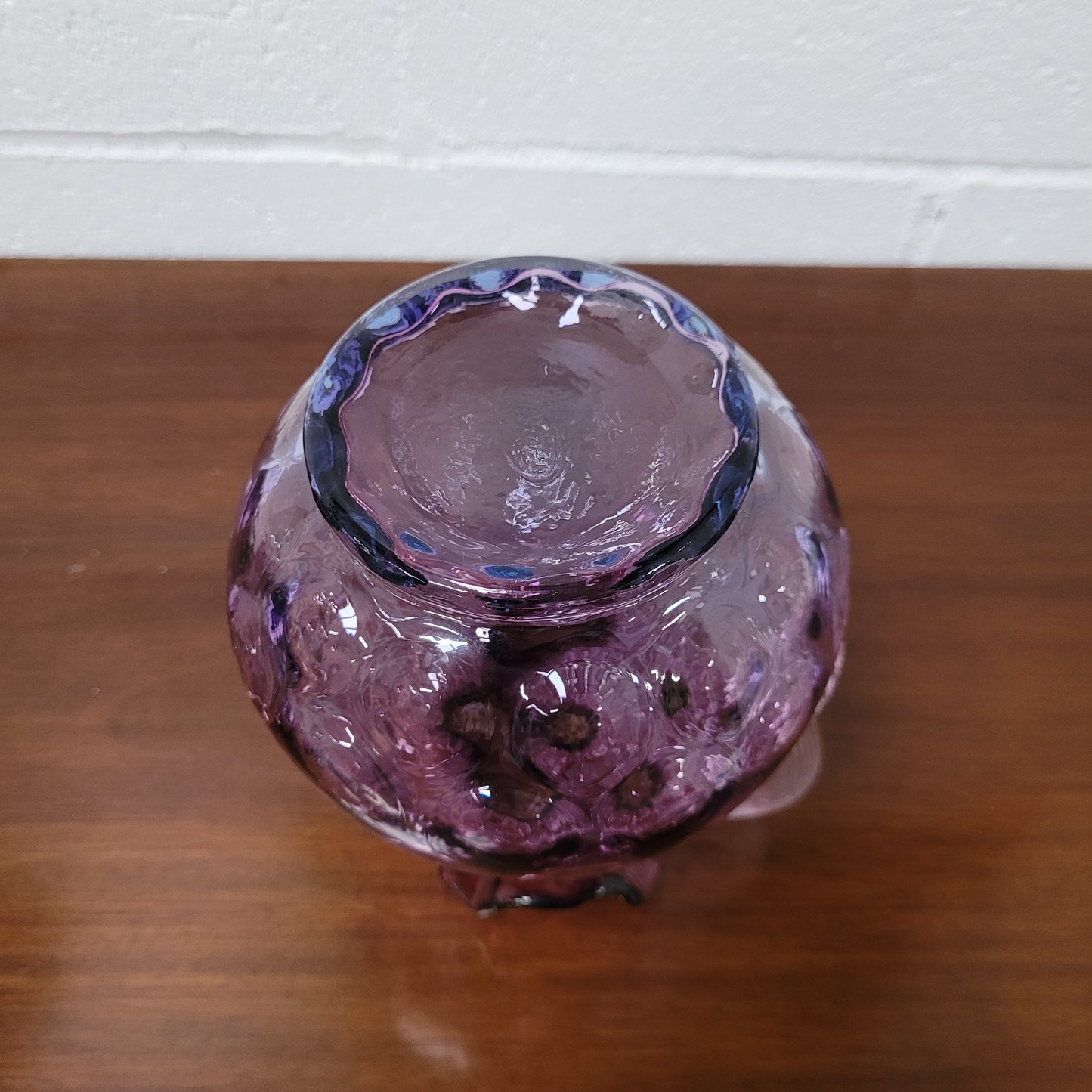 Elegant Fenton Mulberry / Amethyst glass jug in the inverted thumbprint style. It has a clear stretched glass handle and a ruffled top with a touch of blue at the base. In excellent condition.