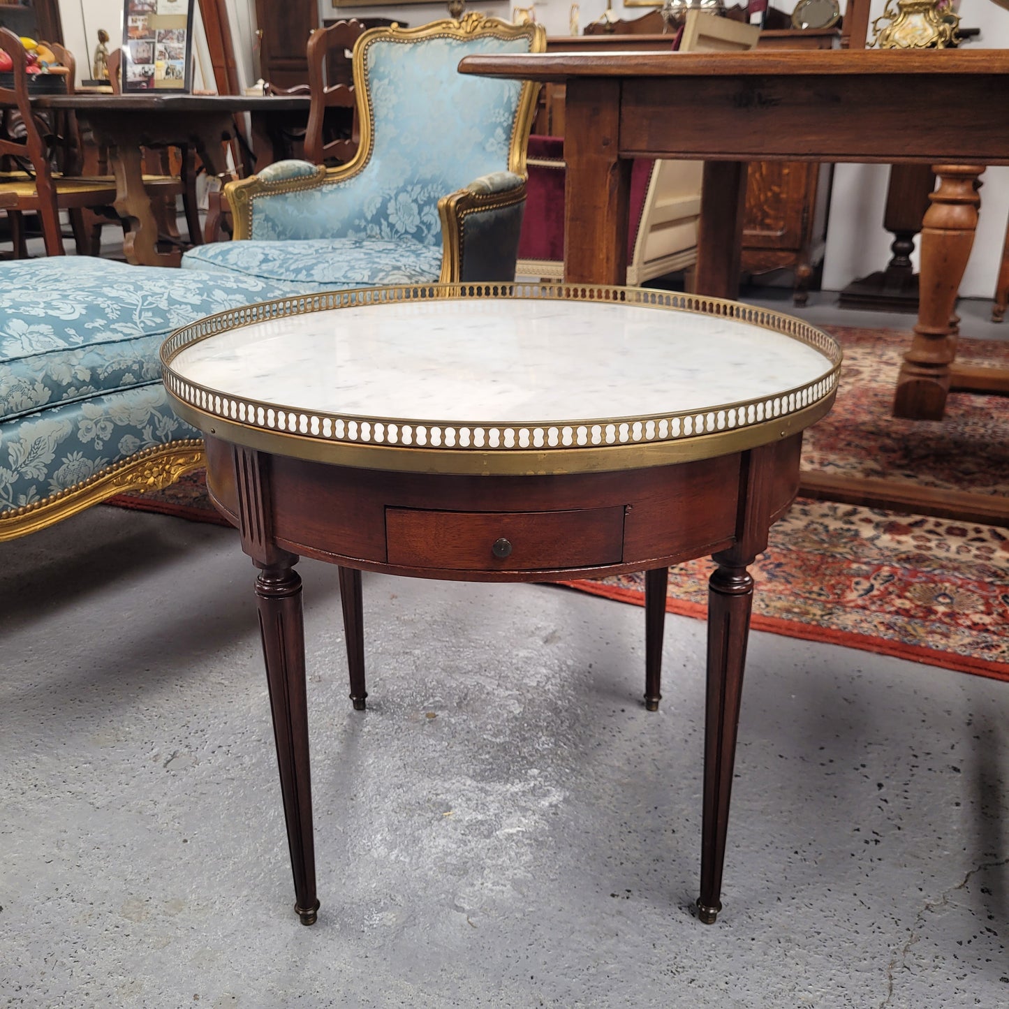 French Louis XVI style Mahogany Bouillotte table, featuring original white Carrara marble top finished nicely with a gilt brass gallery and standing on elegant tapered and fluted legs. It consists of two drawers and two slide-out extensions with leather inserts. Sourced from France and in good original detailed condition. Circa 1930.