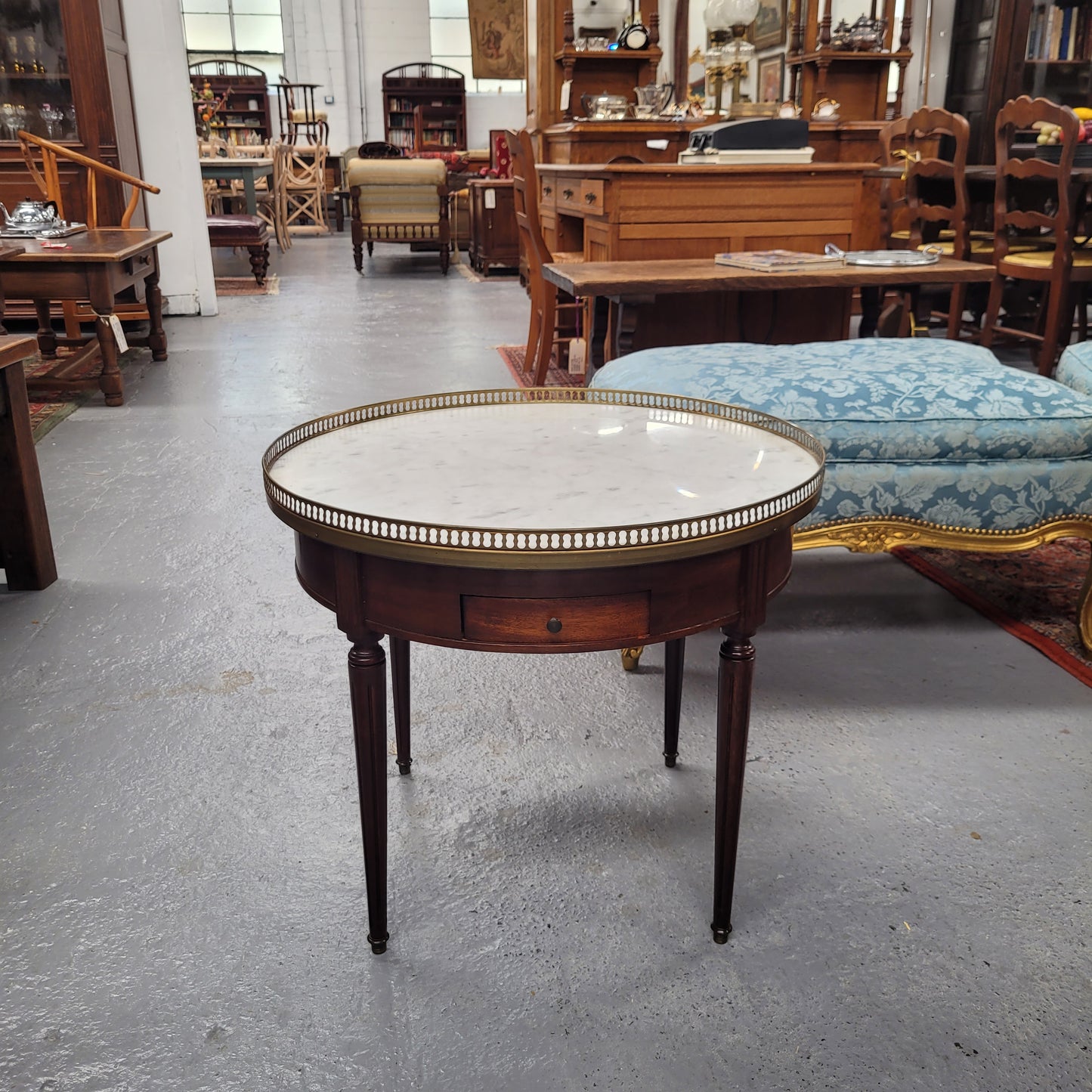 French Louis XVI style Mahogany Bouillotte table, featuring original white Carrara marble top finished nicely with a gilt brass gallery and standing on elegant tapered and fluted legs. It consists of two drawers and two slide-out extensions with leather inserts. Sourced from France and in good original detailed condition. Circa 1930.