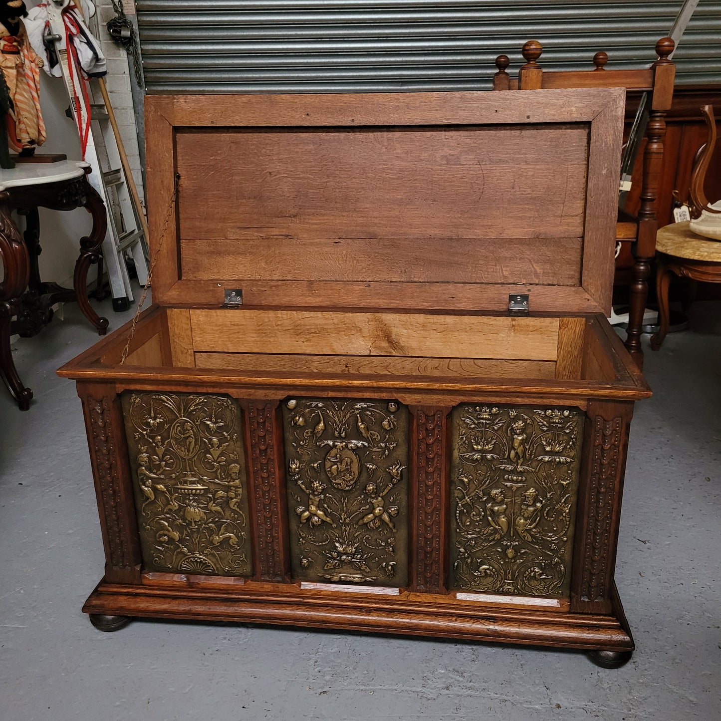 Antique French Oak coffer featuring decorative brass panels and a faux leather top. Brass panels are highly decorative featuring cherubs and faux leather in good used condition with very small signs of wear