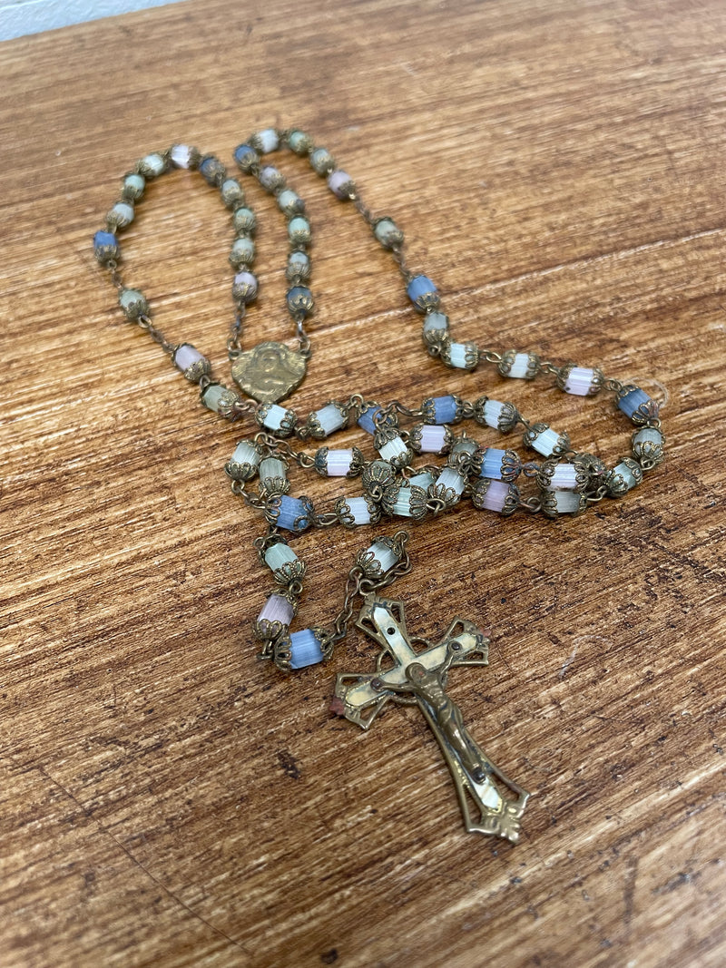 Antique rosary with gilt metal beads and cut crystal, featuring a cross and a Virgin Mary medal, laid out on a wooden surface.