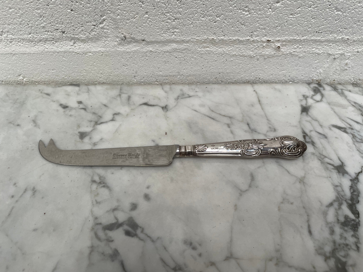 Decorative Sheffield sterling silver cheese knife. The handle has sterling silver hallmarks and the blade is stainless steel. Made in England and is in good original condition.