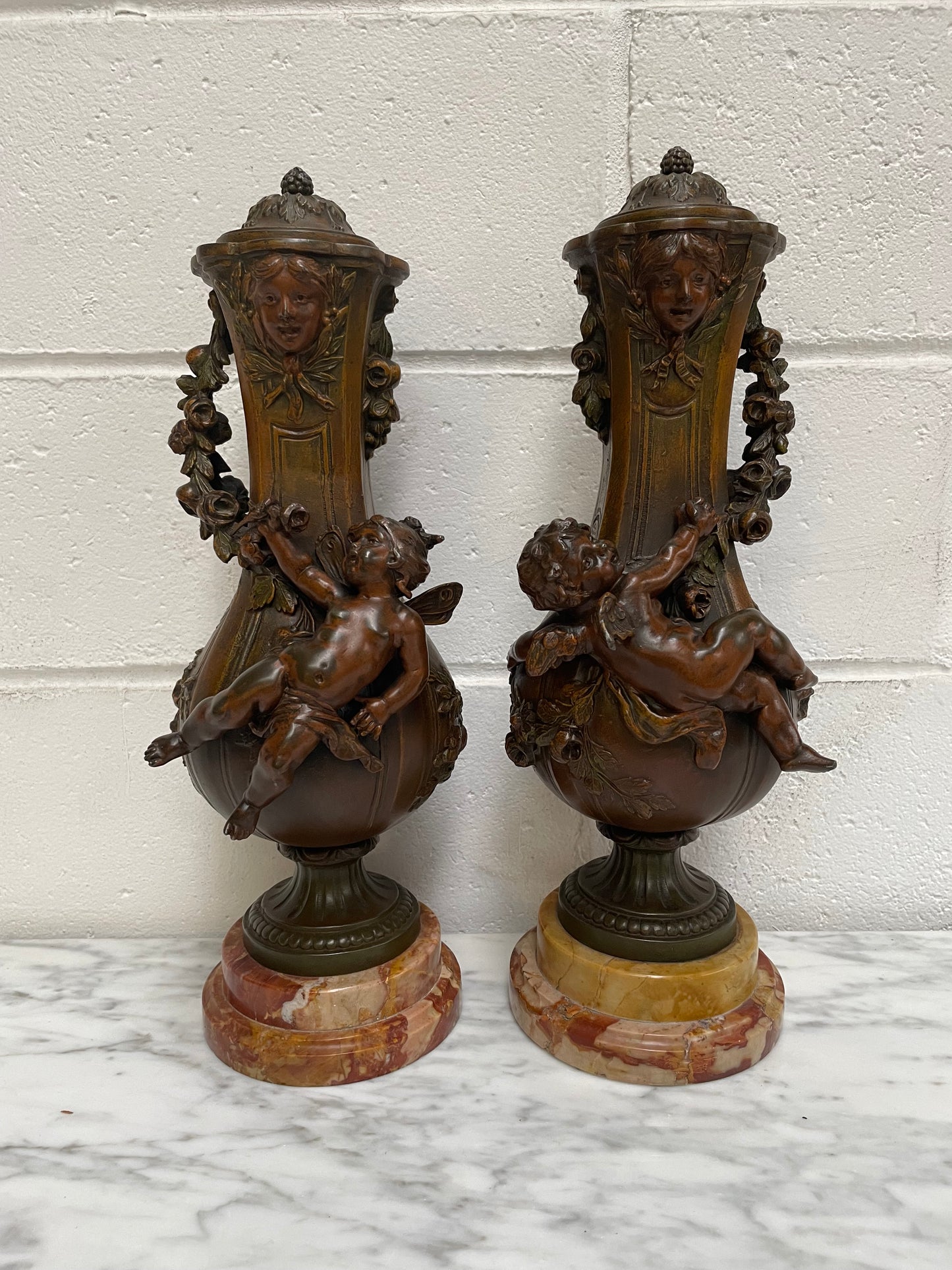 Pair of French Bronzed Metal Cherub Urns on a Marble Base