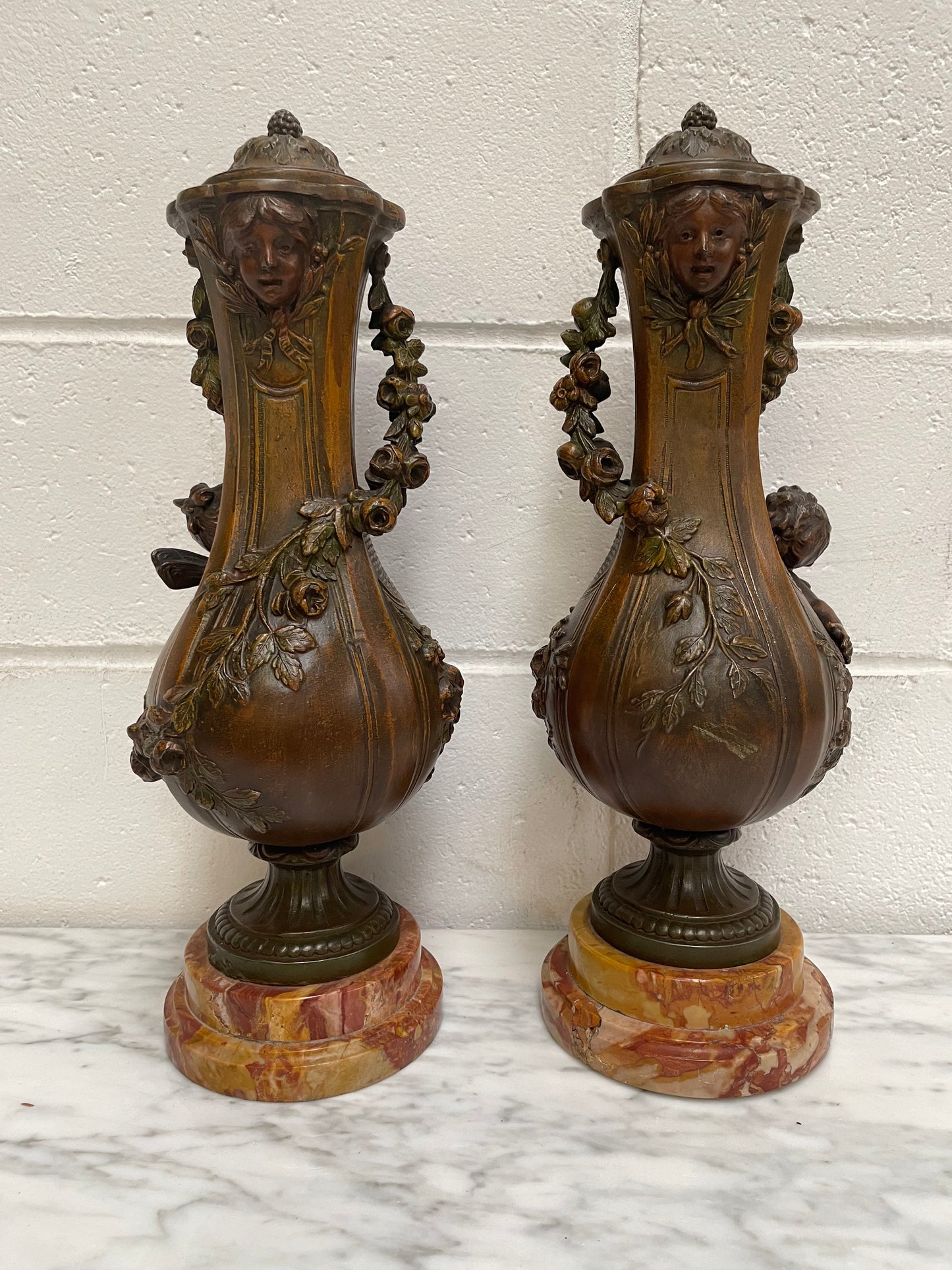 Pair of French Bronzed Metal Cherub Urns on a Marble Base