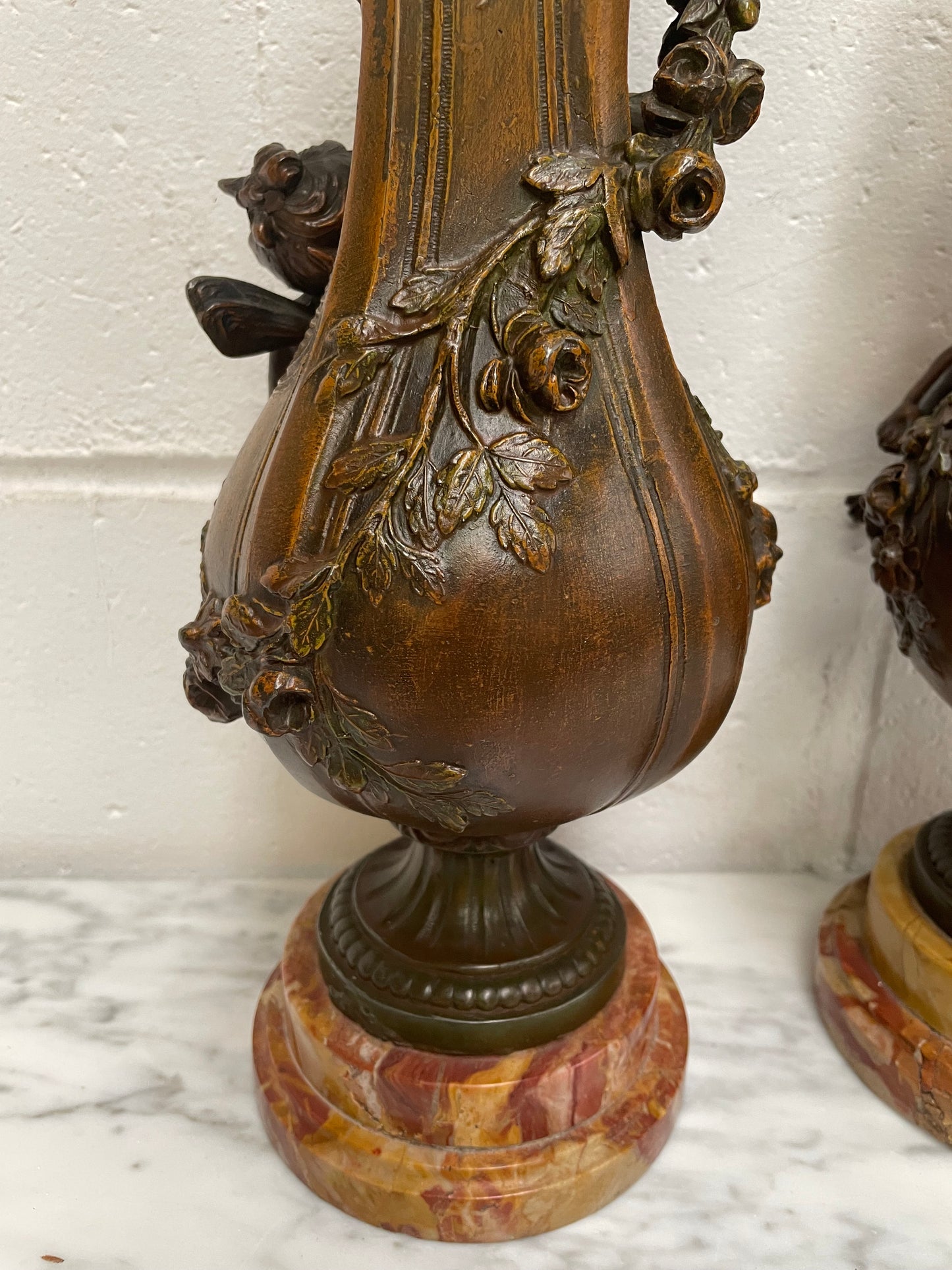 Pair of French Bronzed Metal Cherub Urns on a Marble Base