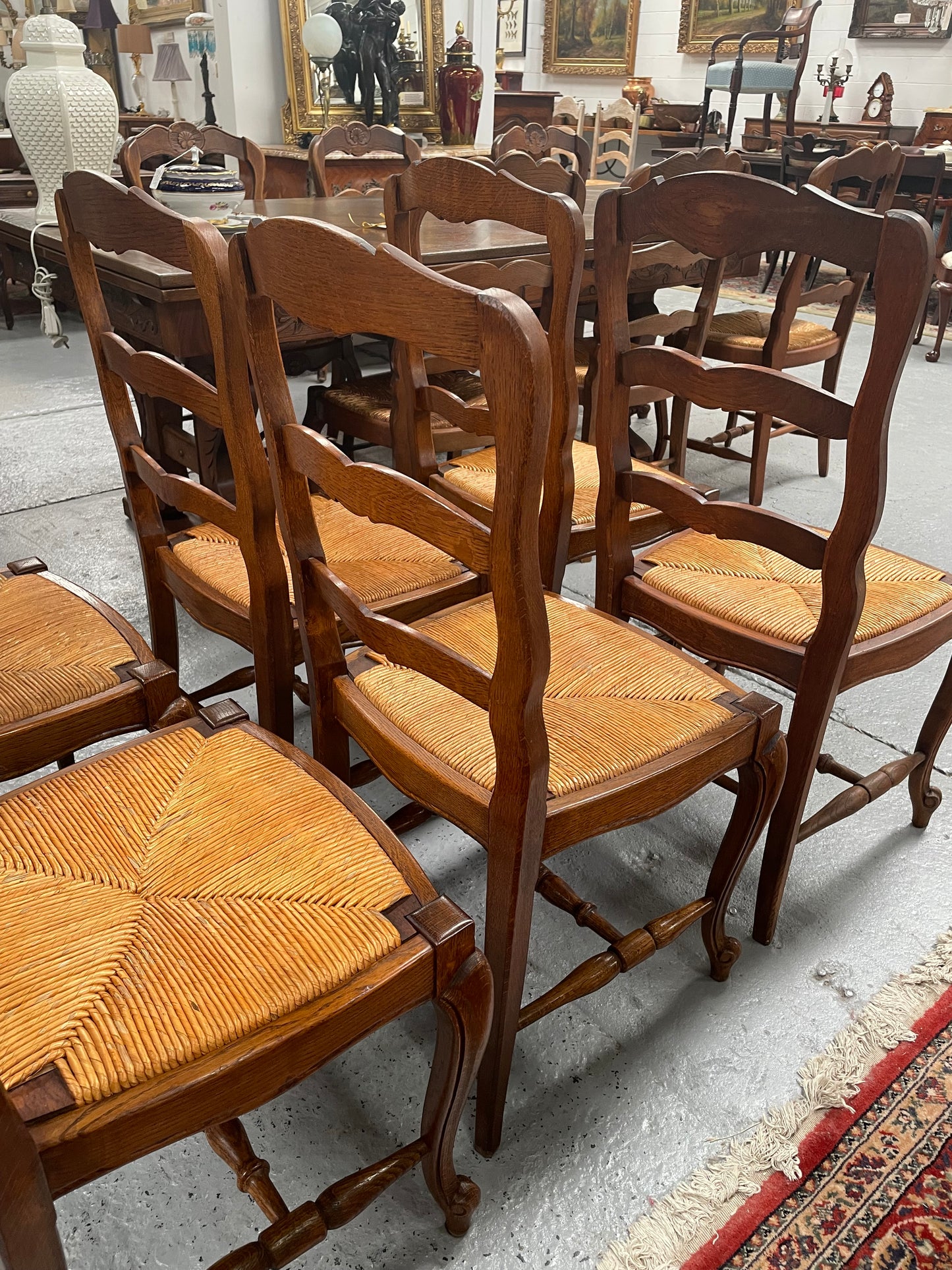 Lovely set of six French rush seat dining chairs. They feature decorative carved detailing particularly to the top of the chair. They are in good original detailed condition and have been sourced from France.