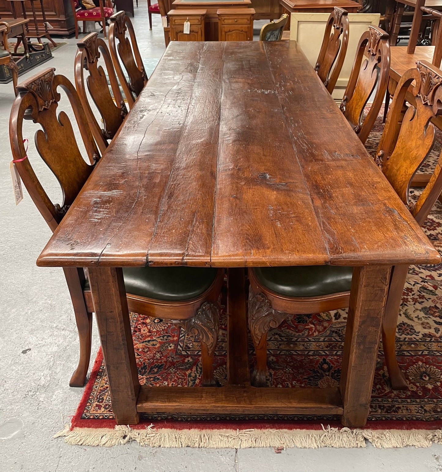 Rustic stretcher base dining table. The top consists of four heavy planks of French Oak timber. The surface is rustic and a little uneven and would require the use of place mats to even out. Please see photos as they form part of the description.