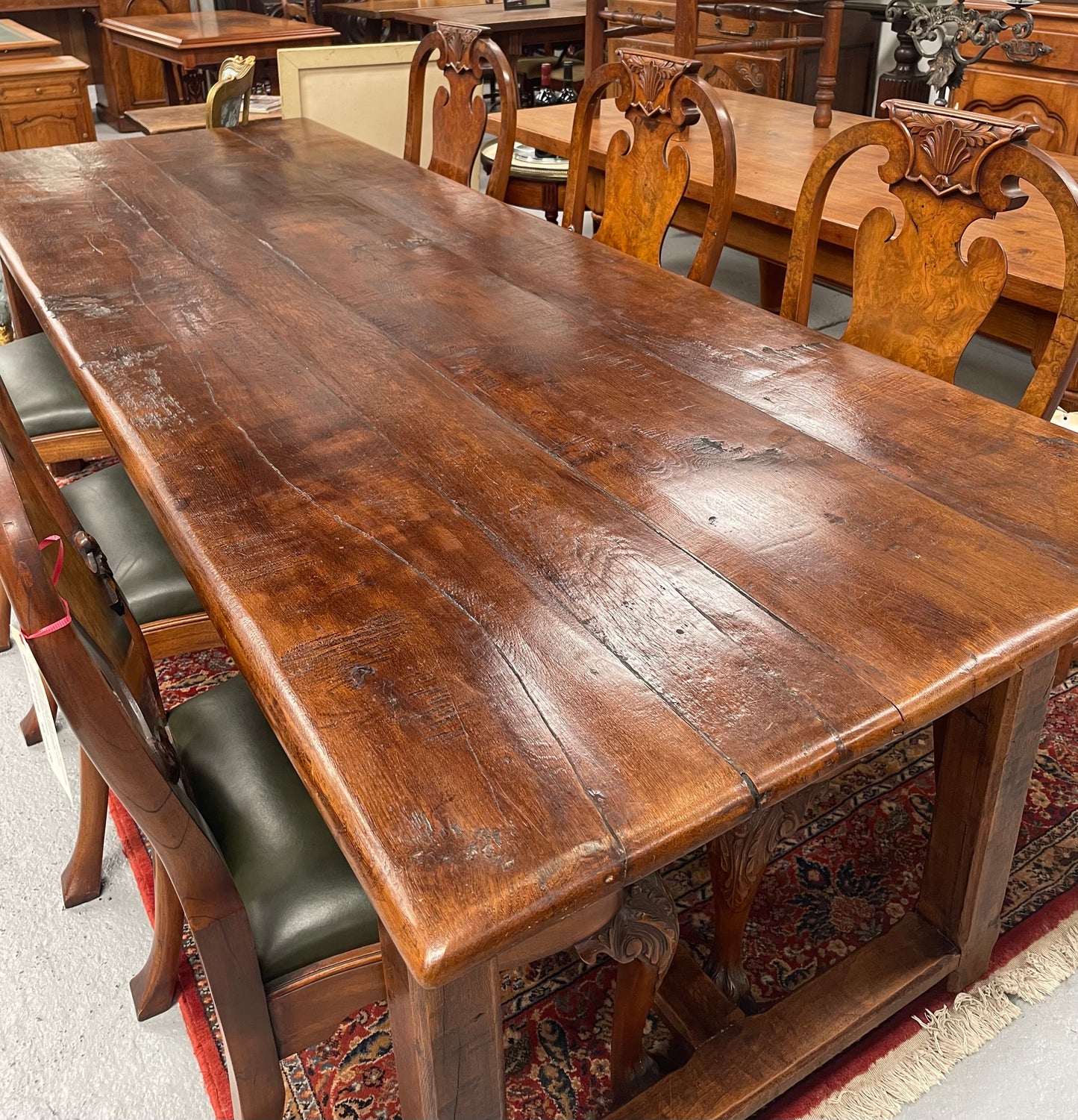 Rustic stretcher base dining table. The top consists of four heavy planks of French Oak timber. The surface is rustic and a little uneven and would require the use of place mats to even out. Please see photos as they form part of the description.