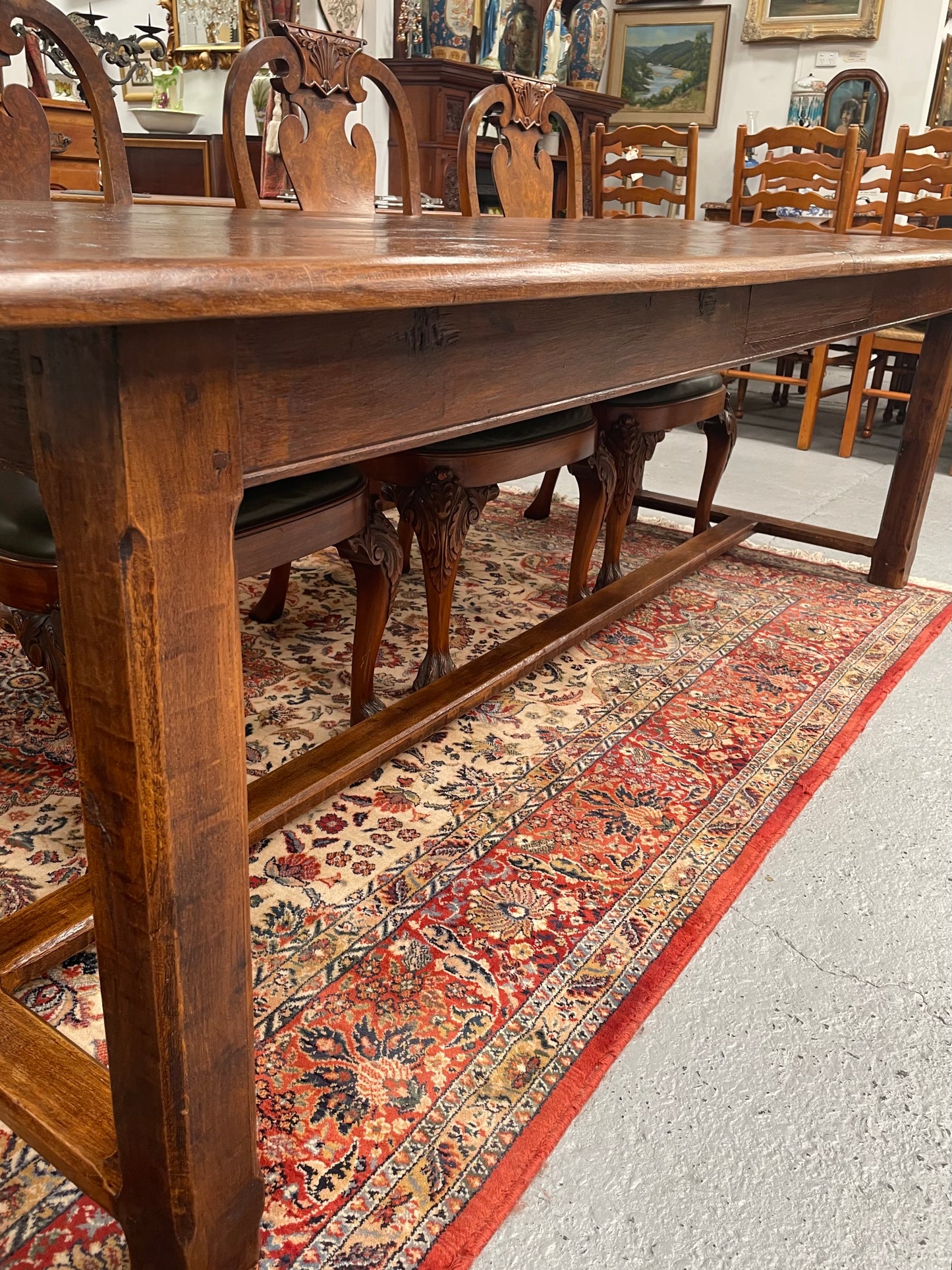Rustic stretcher base dining table. The top consists of four heavy planks of French Oak timber. The surface is rustic and a little uneven and would require the use of place mats to even out. Please see photos as they form part of the description.