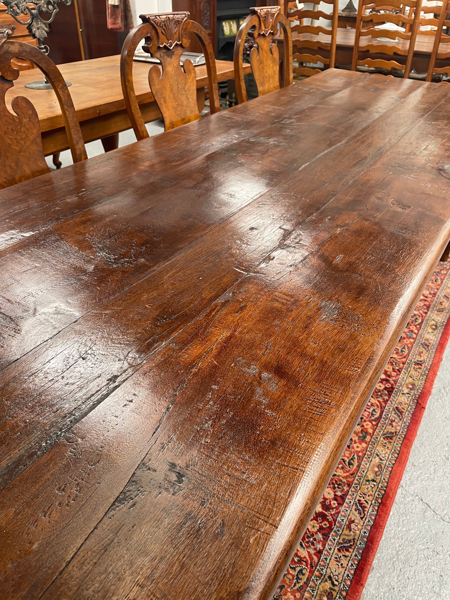 Rustic stretcher base dining table. The top consists of four heavy planks of French Oak timber. The surface is rustic and a little uneven and would require the use of place mats to even out. Please see photos as they form part of the description.