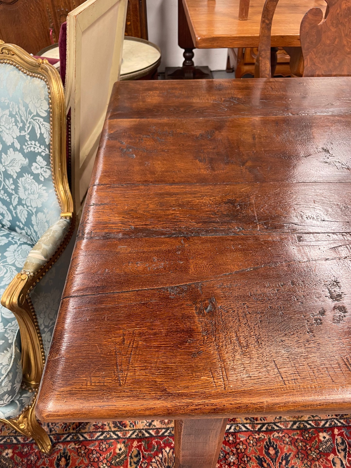 Rustic stretcher base dining table. The top consists of four heavy planks of French Oak timber. The surface is rustic and a little uneven and would require the use of place mats to even out. Please see photos as they form part of the description.