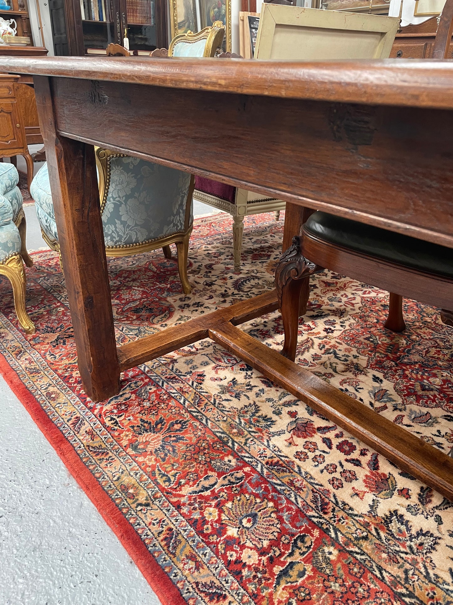 Rustic stretcher base dining table. The top consists of four heavy planks of French Oak timber. The surface is rustic and a little uneven and would require the use of place mats to even out. Please see photos as they form part of the description.