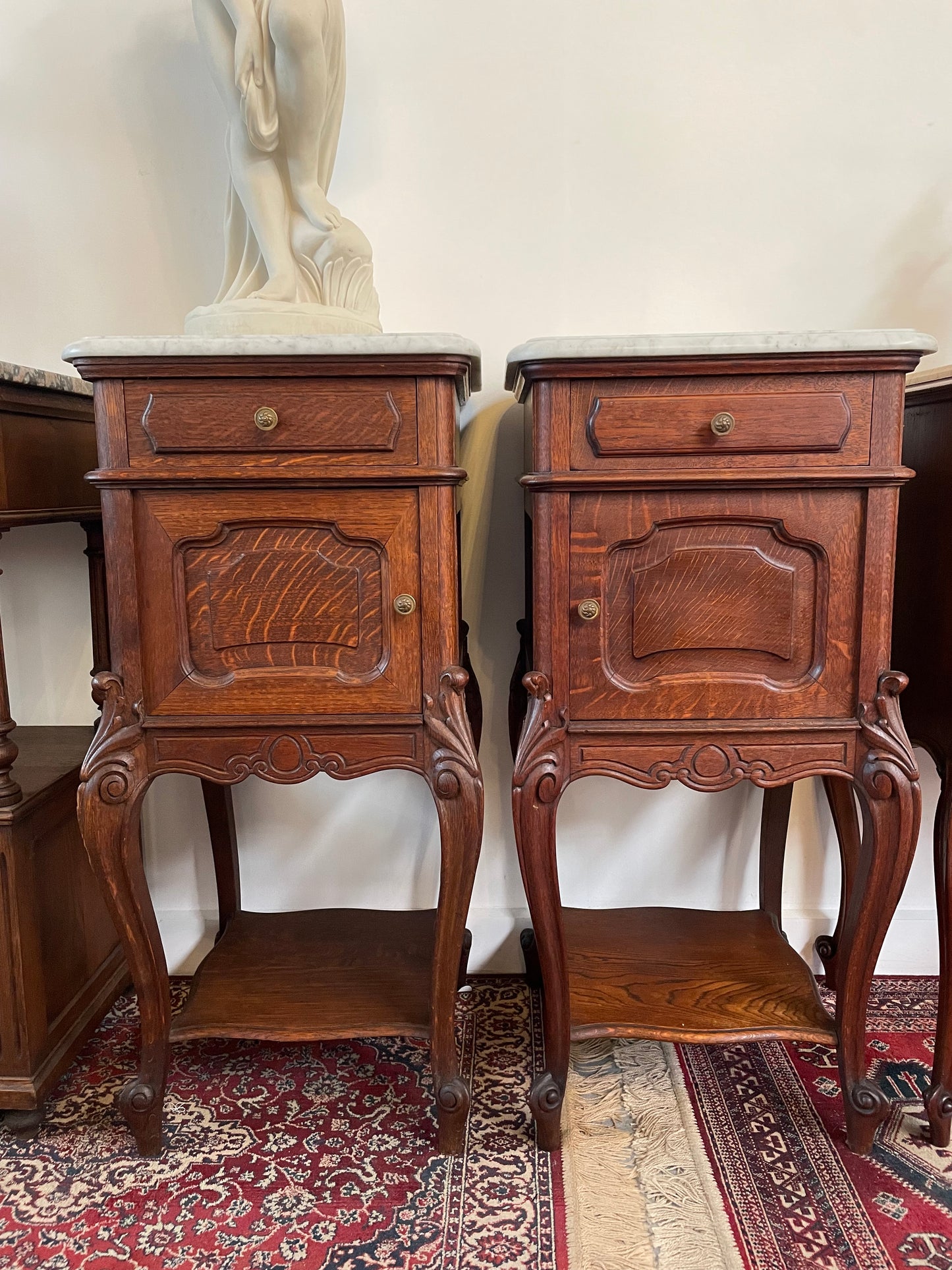 Beautifully carved pair of French Oak bedside cabinets with marble tops and inserts . They consist of one drawer and one cupboard. Featuring classic Louis 15th style curved legs and in good original detailed condition. They have been imported directly from France.