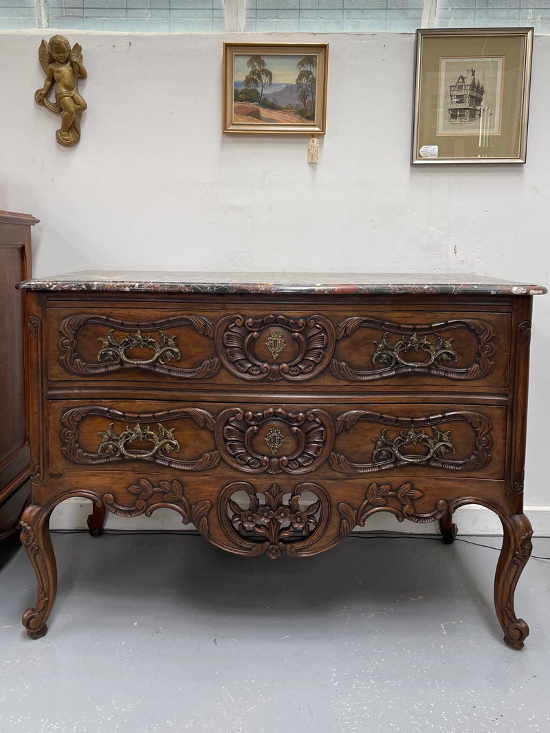 Highly decorative Louis XIV black marble topped two drawer commode. Featuring carved drawer fronts, brass handles and escutcheons. In good detailed detailed condition.