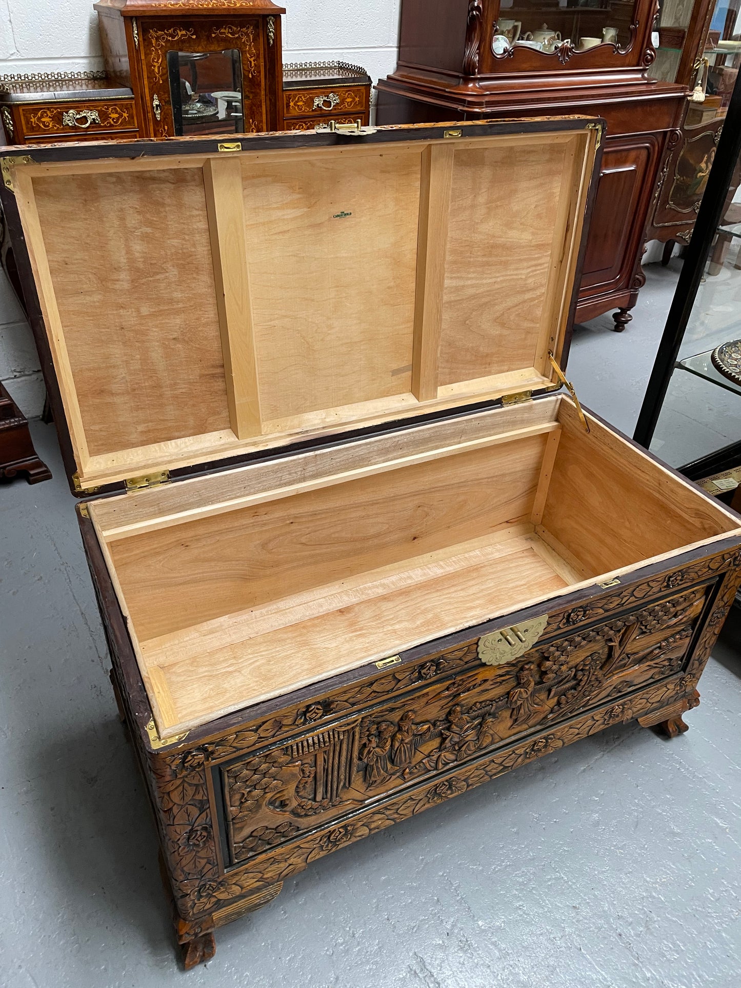 Vintage Chinese carved camphorwood chest with brass lock.; Carving depicts a Chinese domestic scene. It is raised on four carved feet. In good original detailed condition.