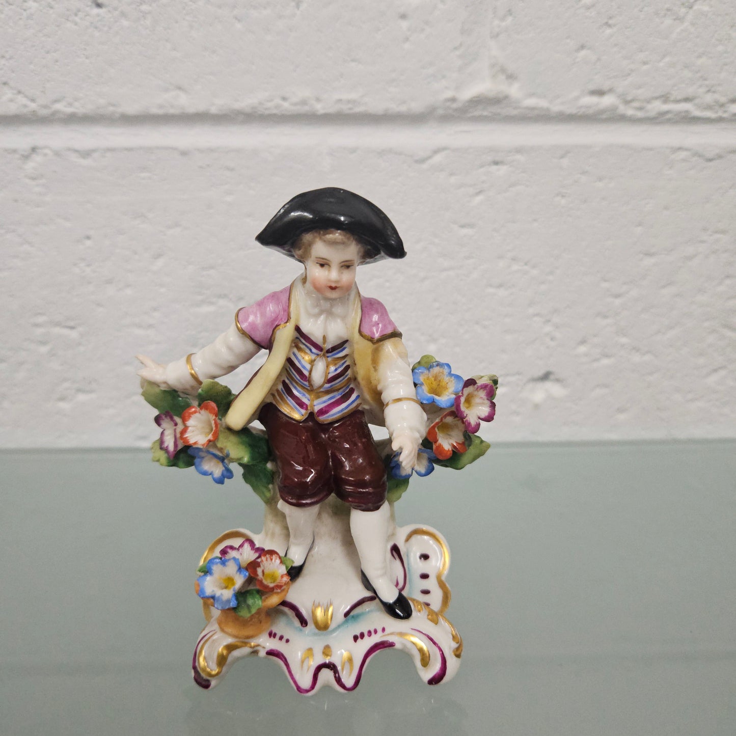 Stunning detailed early figure of a boy with flowers, there is a gold anchor mark to the back of the statue. It is in good original condition with some missing parts on the flowers as