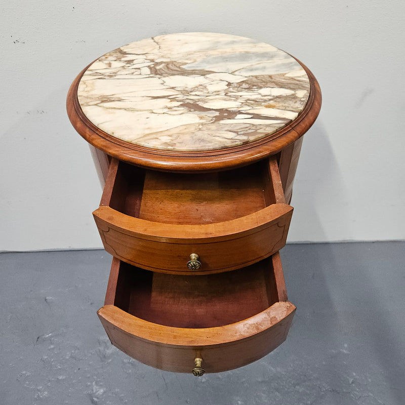 Charming Louis XVI style round side table. Features two drawers, fitted marble top and fluted legs connected by a cane shelf. Sourced directly from France and is in good original detailed condition.