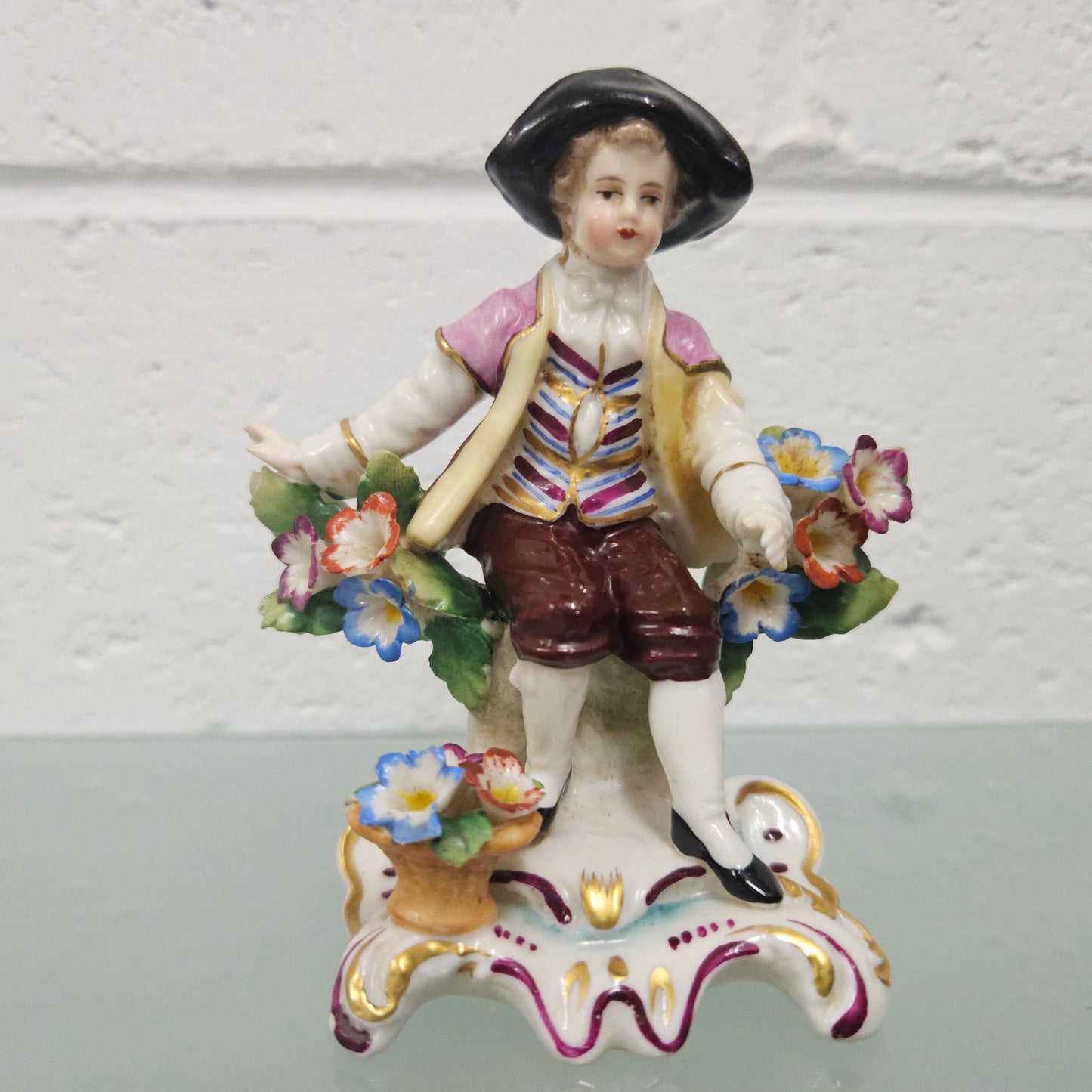 Stunning detailed early figure of a boy with flowers, there is a gold anchor mark to the back of the statue. It is in good original condition with some missing parts on the flowers as