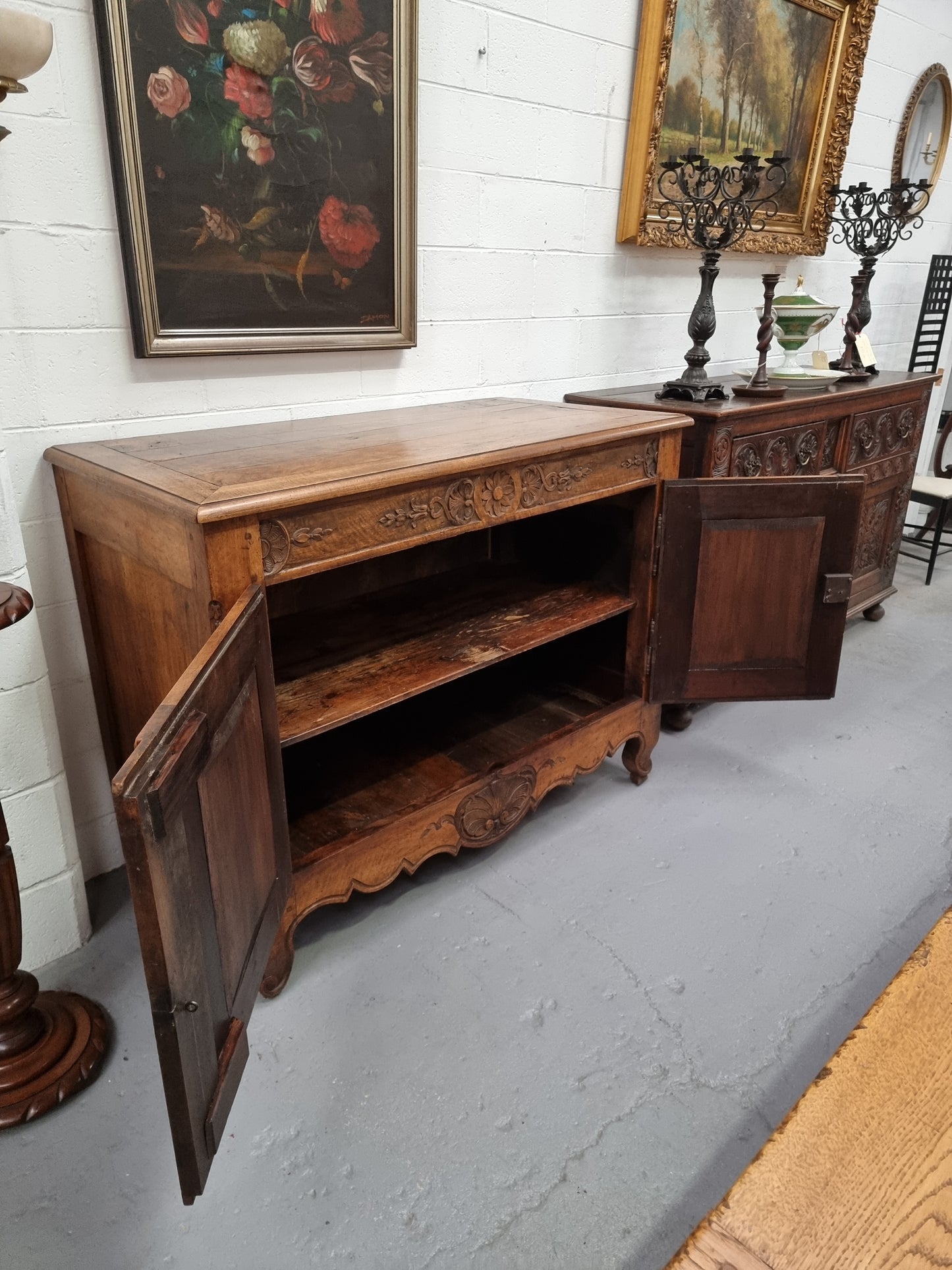 Vintage wooden cabinet with open door in a room with white walls and framed artwork.