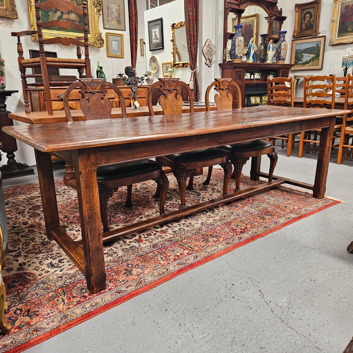 Rustic stretcher base dining table. The top consists of four heavy planks of French Oak timber. The surface is rustic and a little uneven and would require the use of place mats to even out. Please see photos as they form part of the description.