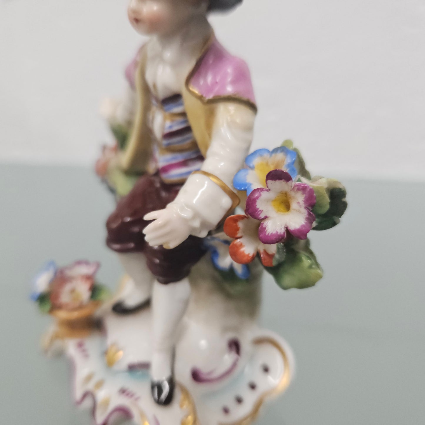 Stunning detailed early figure of a boy with flowers, there is a gold anchor mark to the back of the statue. It is in good original condition with some missing parts on the flowers as