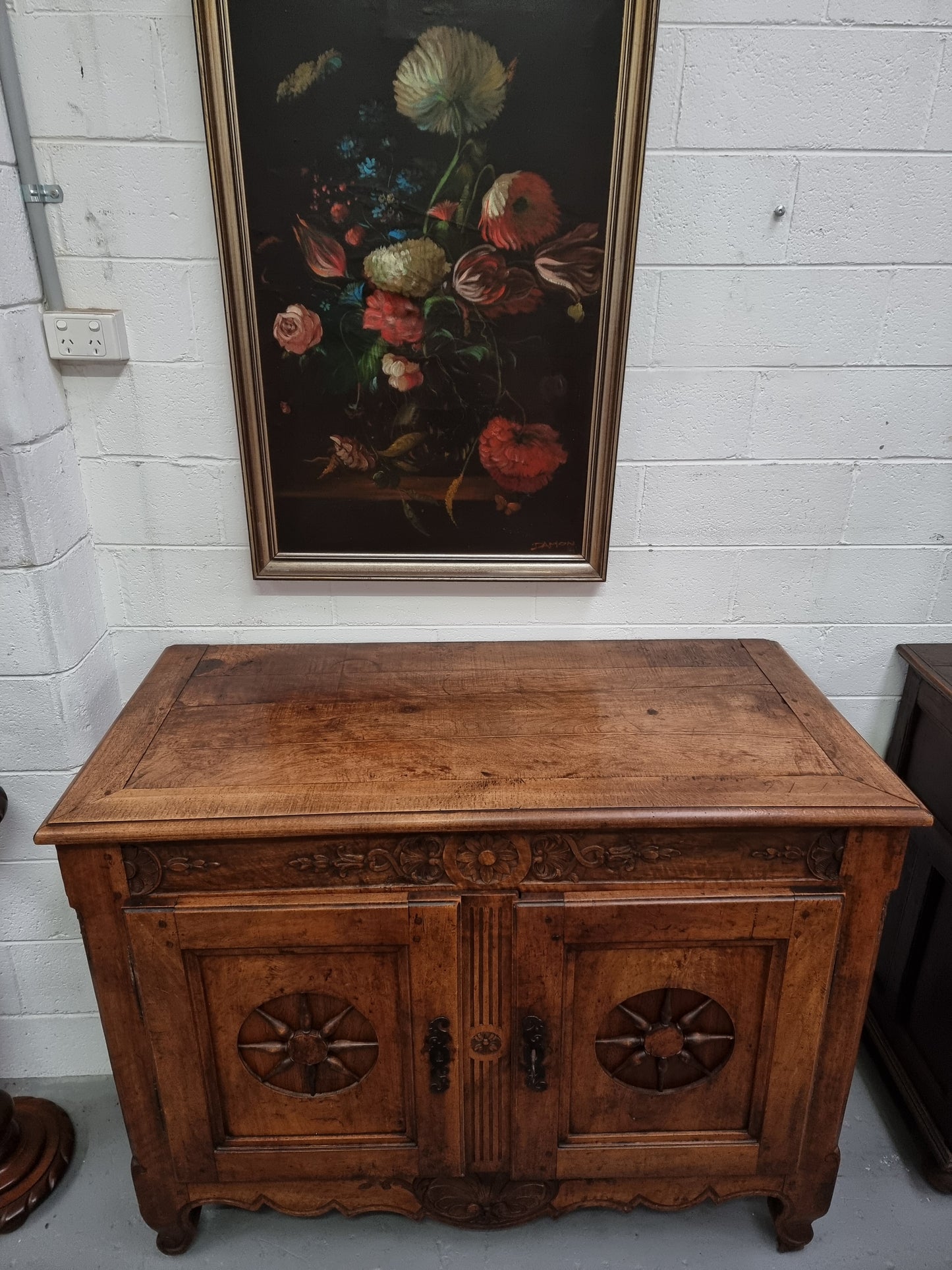 Wooden cabinet with floral painting on a white wall