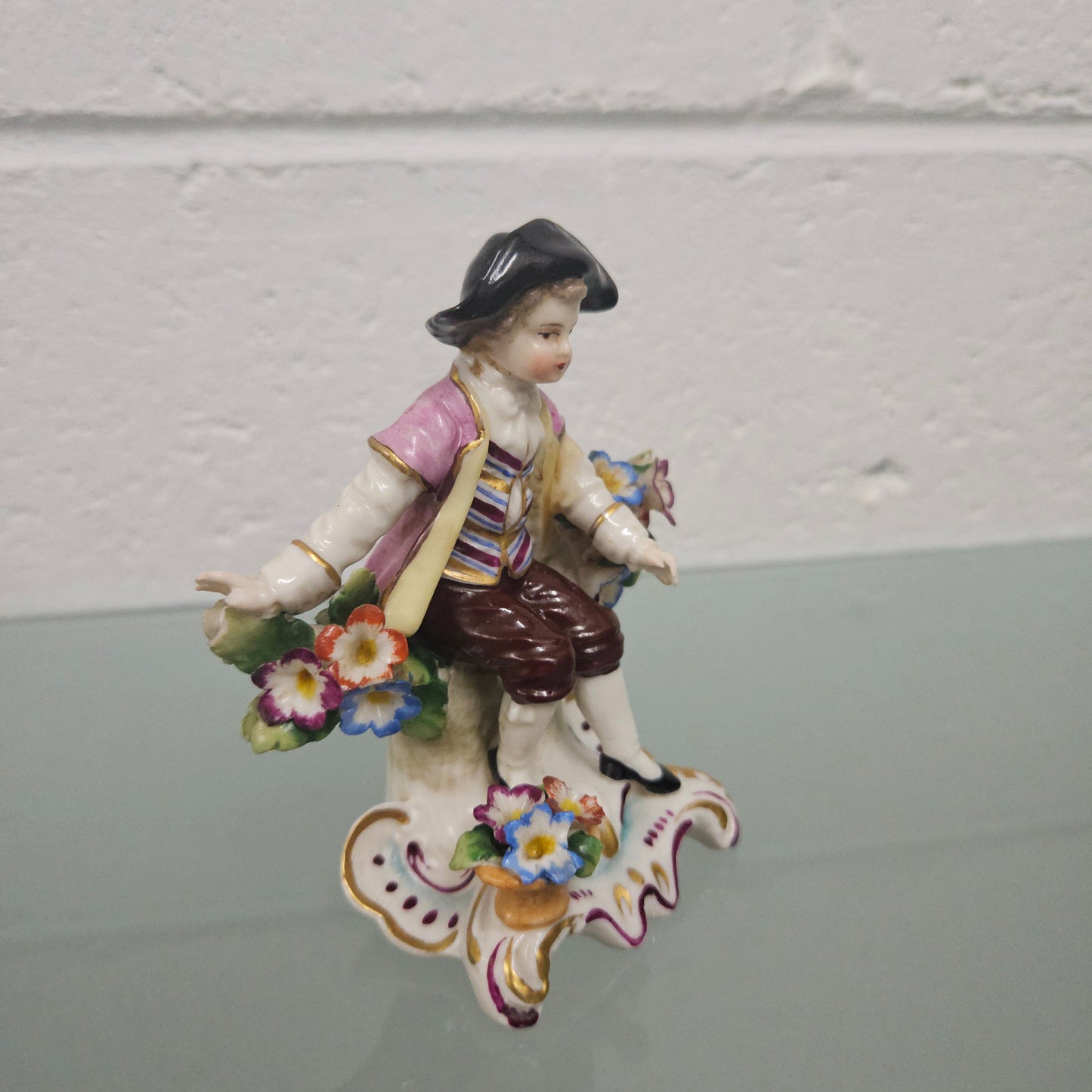 Stunning detailed early figure of a boy with flowers, there is a gold anchor mark to the back of the statue. It is in good original condition with some missing parts on the flowers as