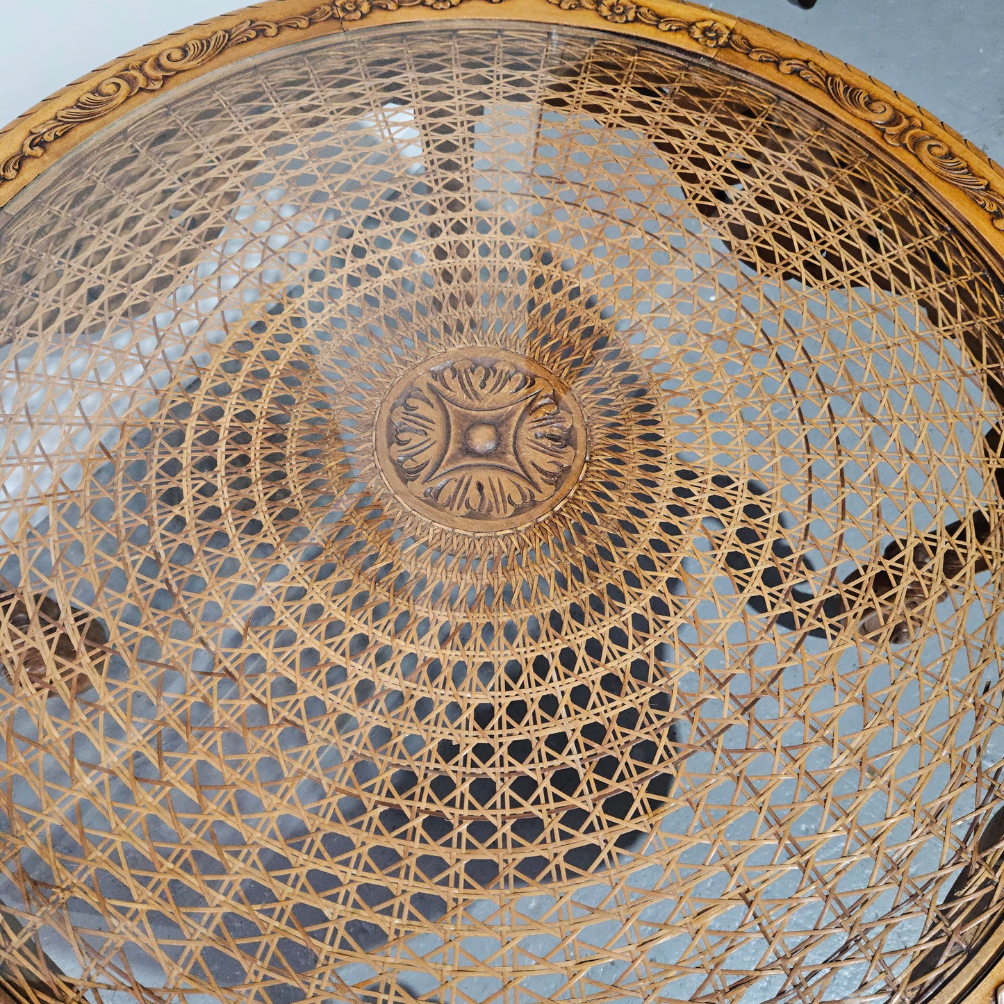 French oak Louis XV style round cane insert coffee table with highly decorative legs and table top. It has a glass cover to fit over the cane. It is in good original condition and has been sourced from France.