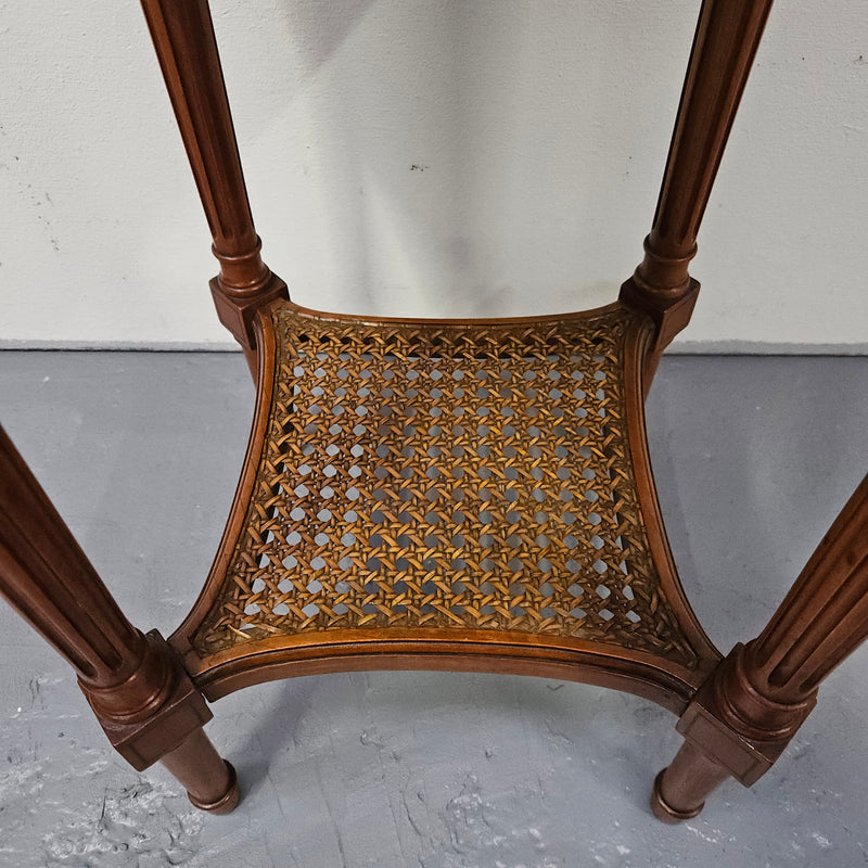 Charming Louis XVI style round side table. Features two drawers, fitted marble top and fluted legs connected by a cane shelf. Sourced directly from France and is in good original detailed condition.