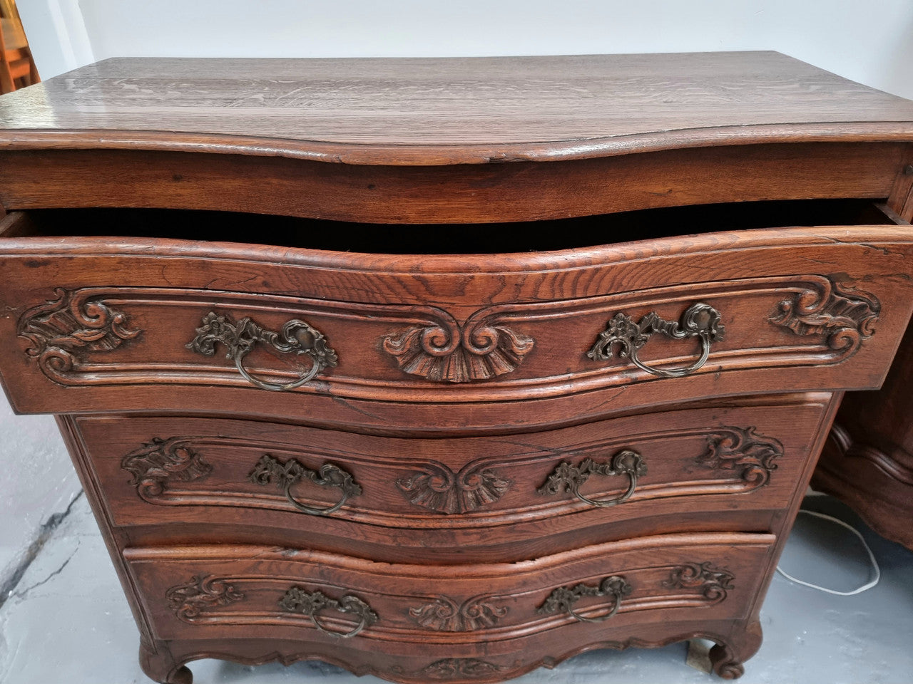 Antique French beautifully carved dark Oak commode with three drawers and ornate handles. It is in good original detailed condition.