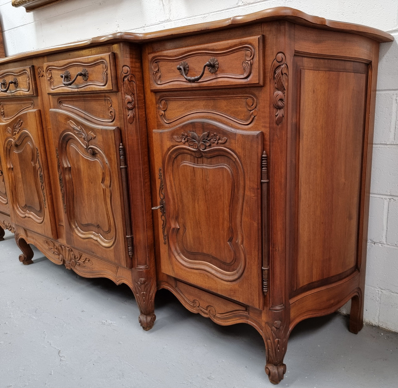 A Beautifully carved French Walnut Louis XV style four door sideboard. Plenty of storage space with four doors as well as four drawers. It is in good original detailed condition.