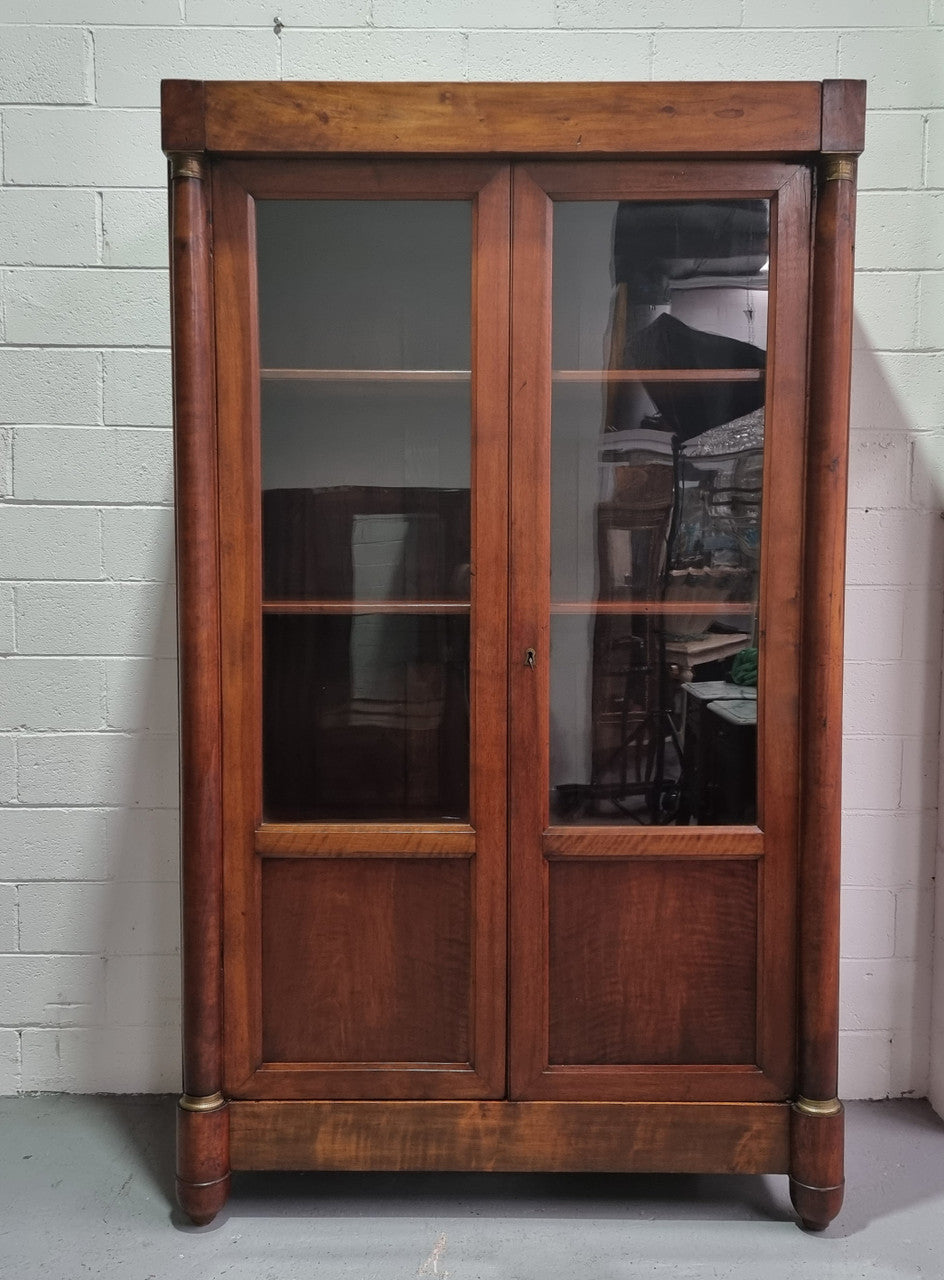 Grand French Mahogany Empire two door bookcase. It has beautiful glass doors and has three fully adjustable shelves. It has been sourced from France and is in good original detailed condition.