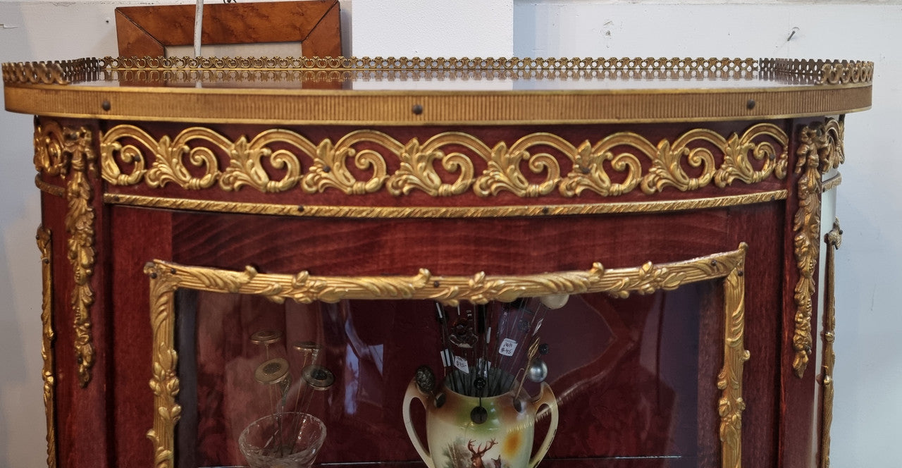 French Mahogany two shelf vitrine with curved glass and brass mounts. It has a lovely frabic interior and two glass shelves. In good original detailed condition.
