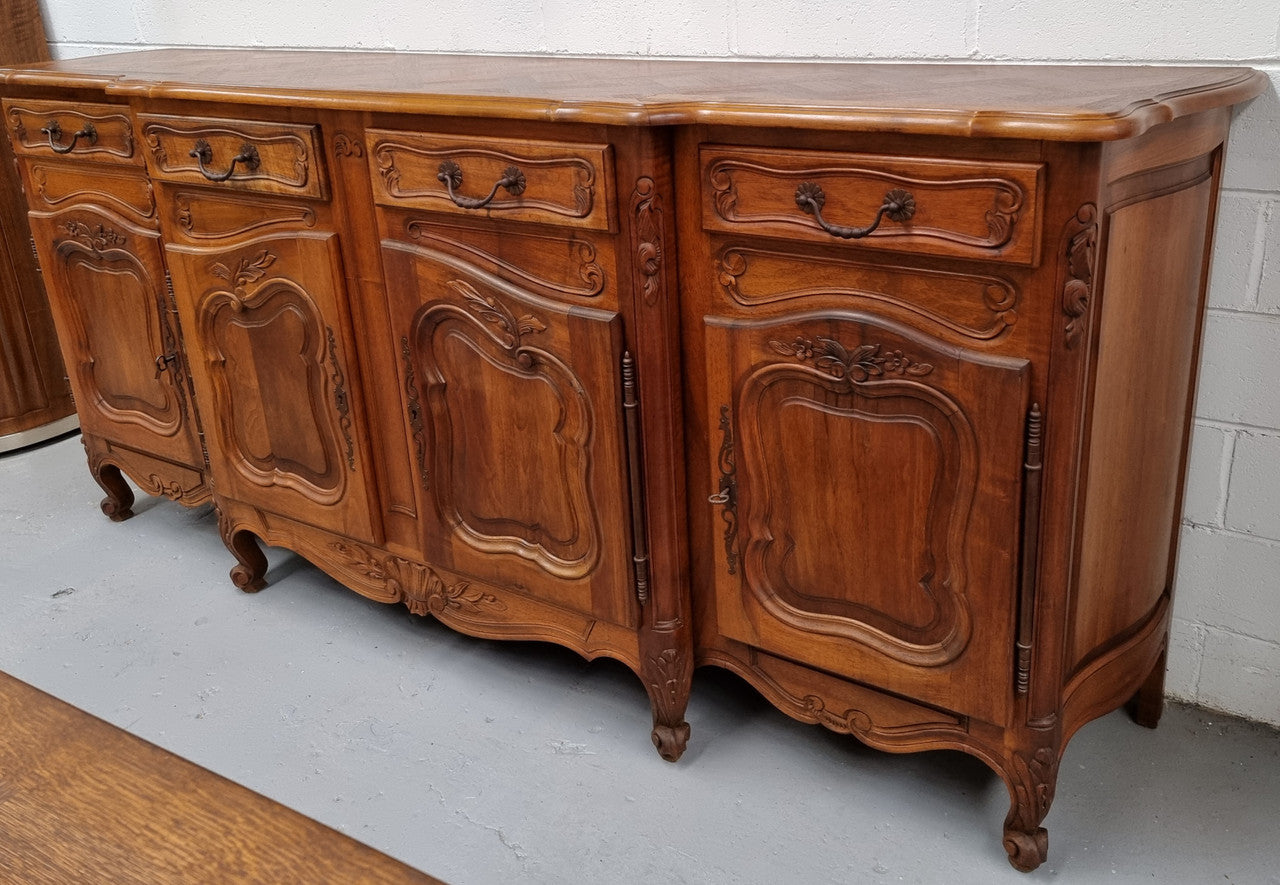 A Beautifully carved French Walnut Louis XV style four door sideboard. Plenty of storage space with four doors as well as four drawers. It is in good original detailed condition.