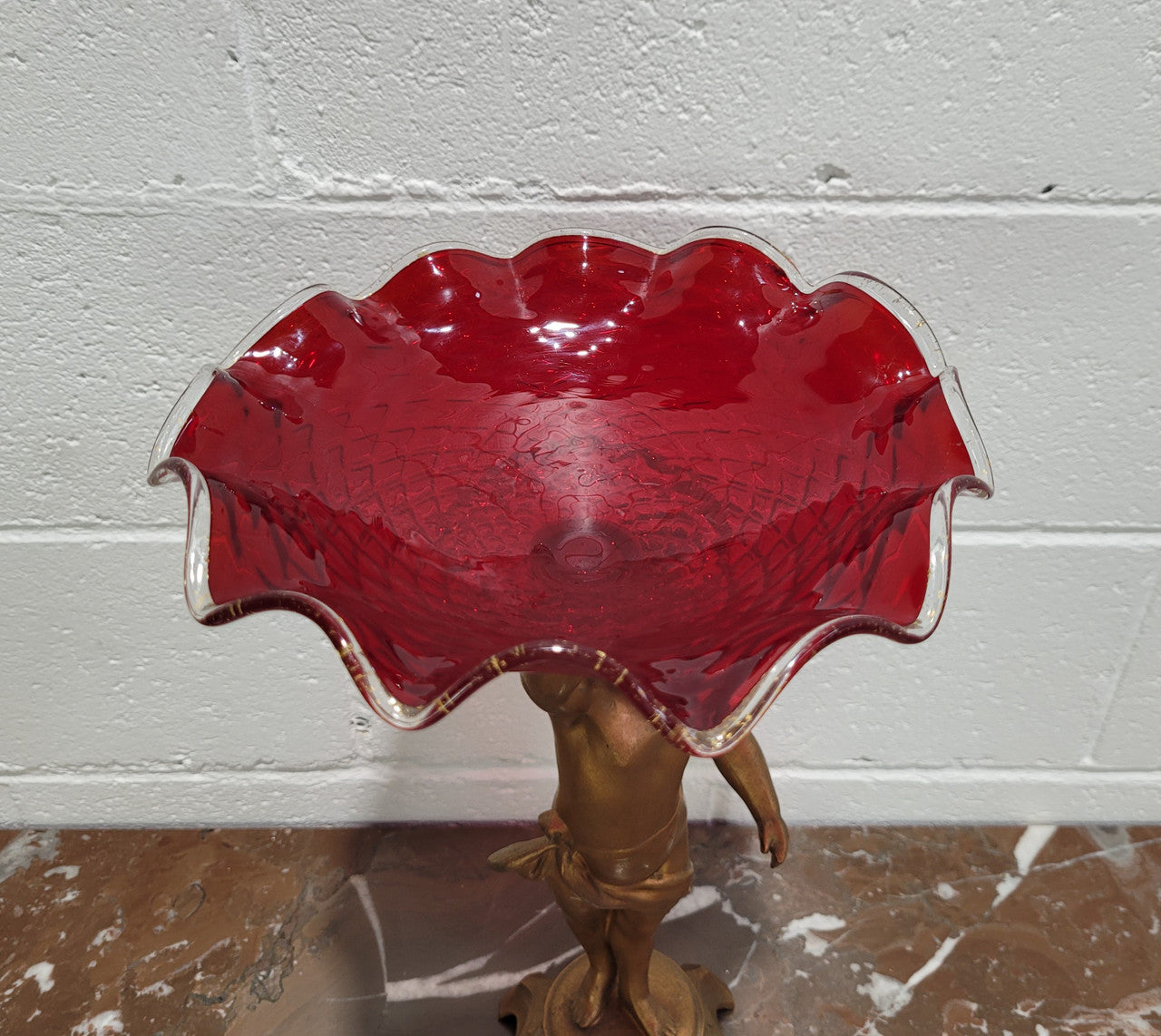 Late Victorian spelter table centerpiece/comfort featuring putti holding ruby glass bowl. In good original condition with no damage to the glass.