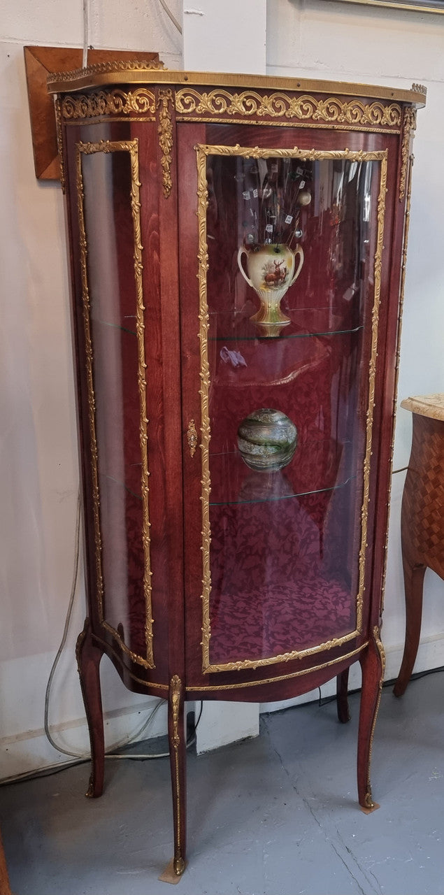 French Mahogany two shelf vitrine with curved glass and brass mounts. It has a lovely frabic interior and two glass shelves. In good original detailed condition.