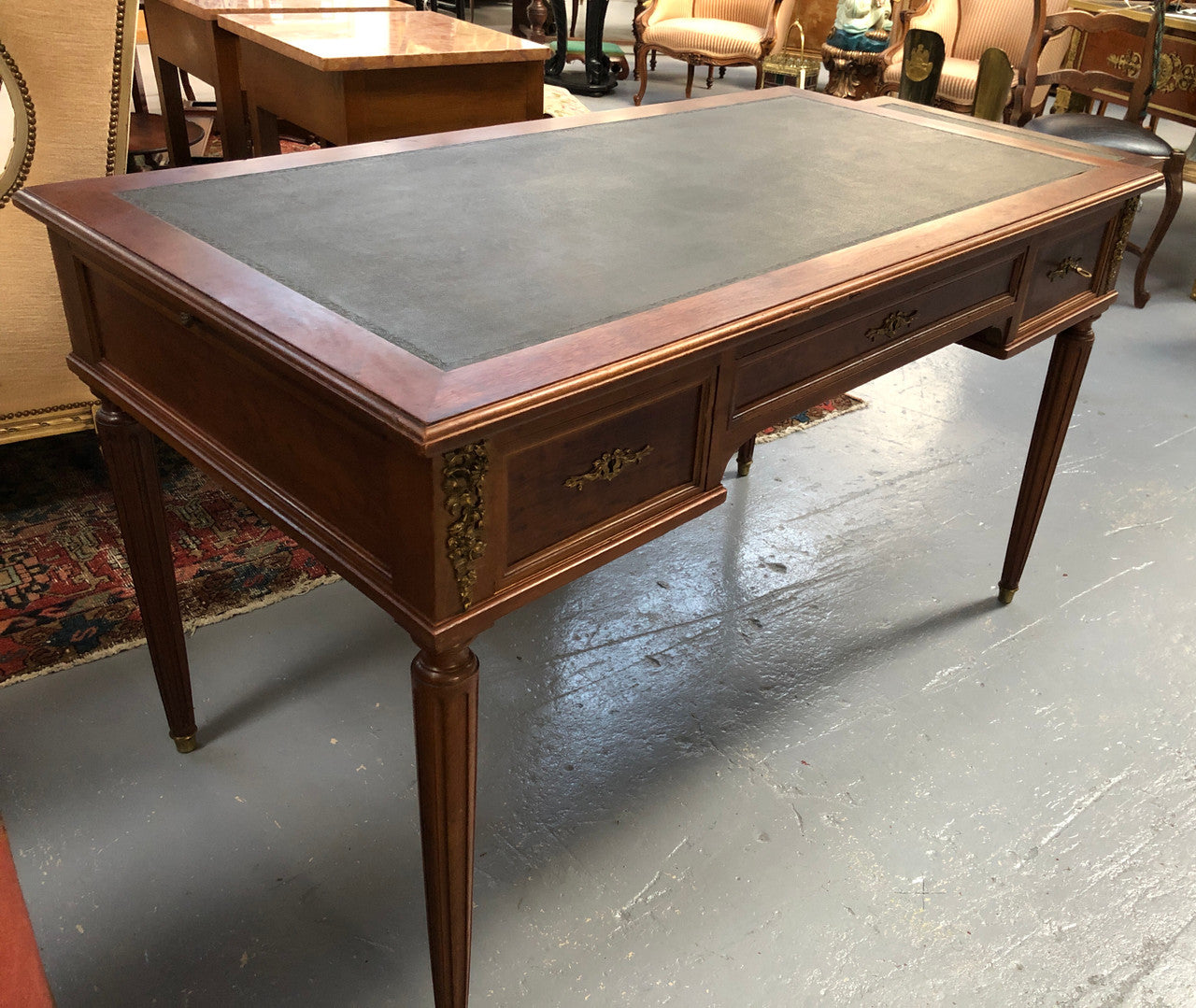 Lovely French Mahogany Louis XVI style leather top desk. With beautiful ormolu details and three drawers. There are also two slides on either side with tooled leather tops and in good original detailed condition.