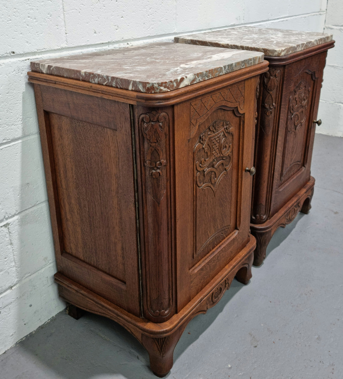 Lovely pair of French oak bedside cabinets with nicely carved details and marble tops. In good original detailed condition.
