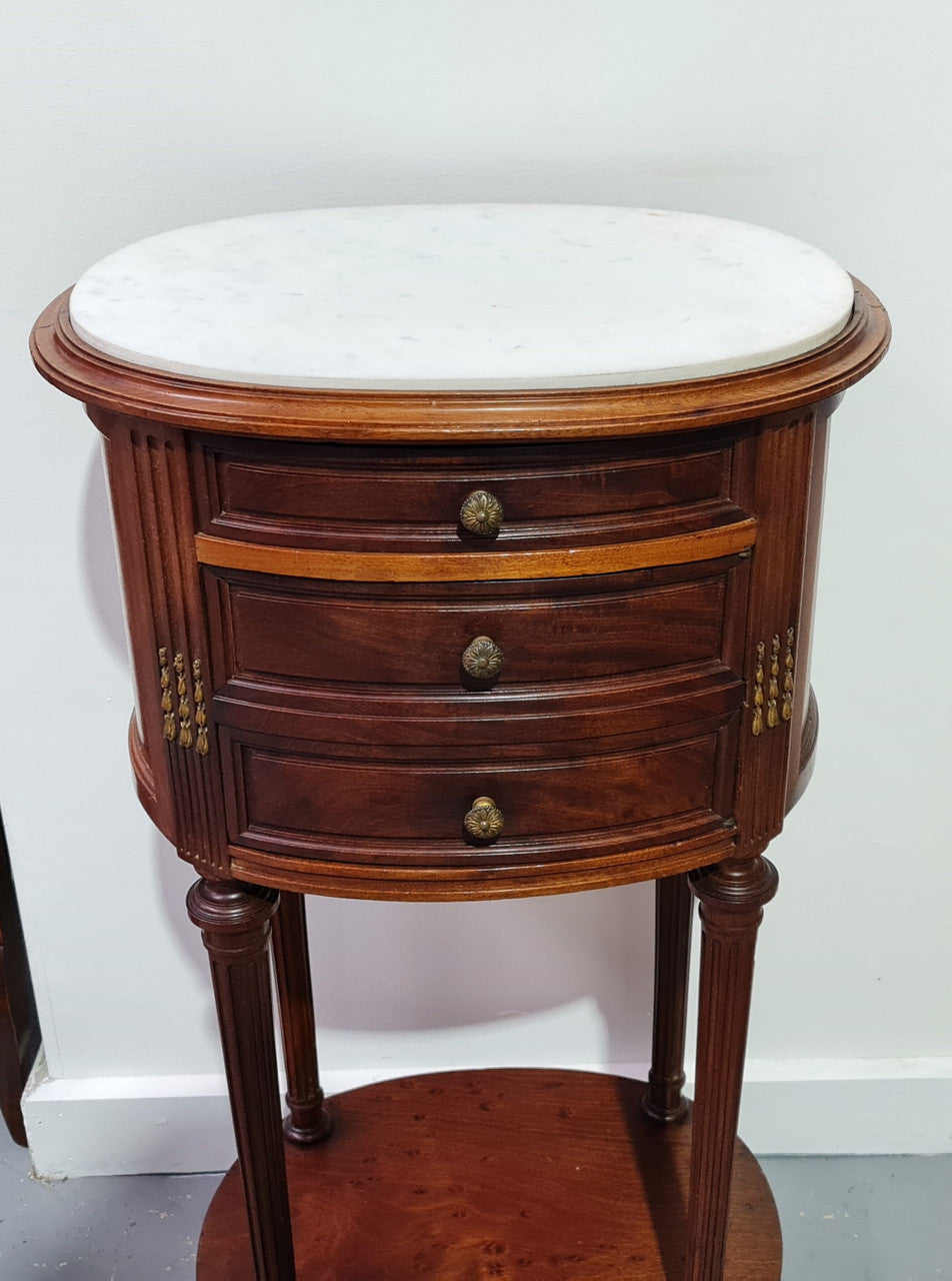 Round Louis XVI style Mahogany marble top side table. It has one drawer and a cupboard for storage. It is in good original detailed condition.