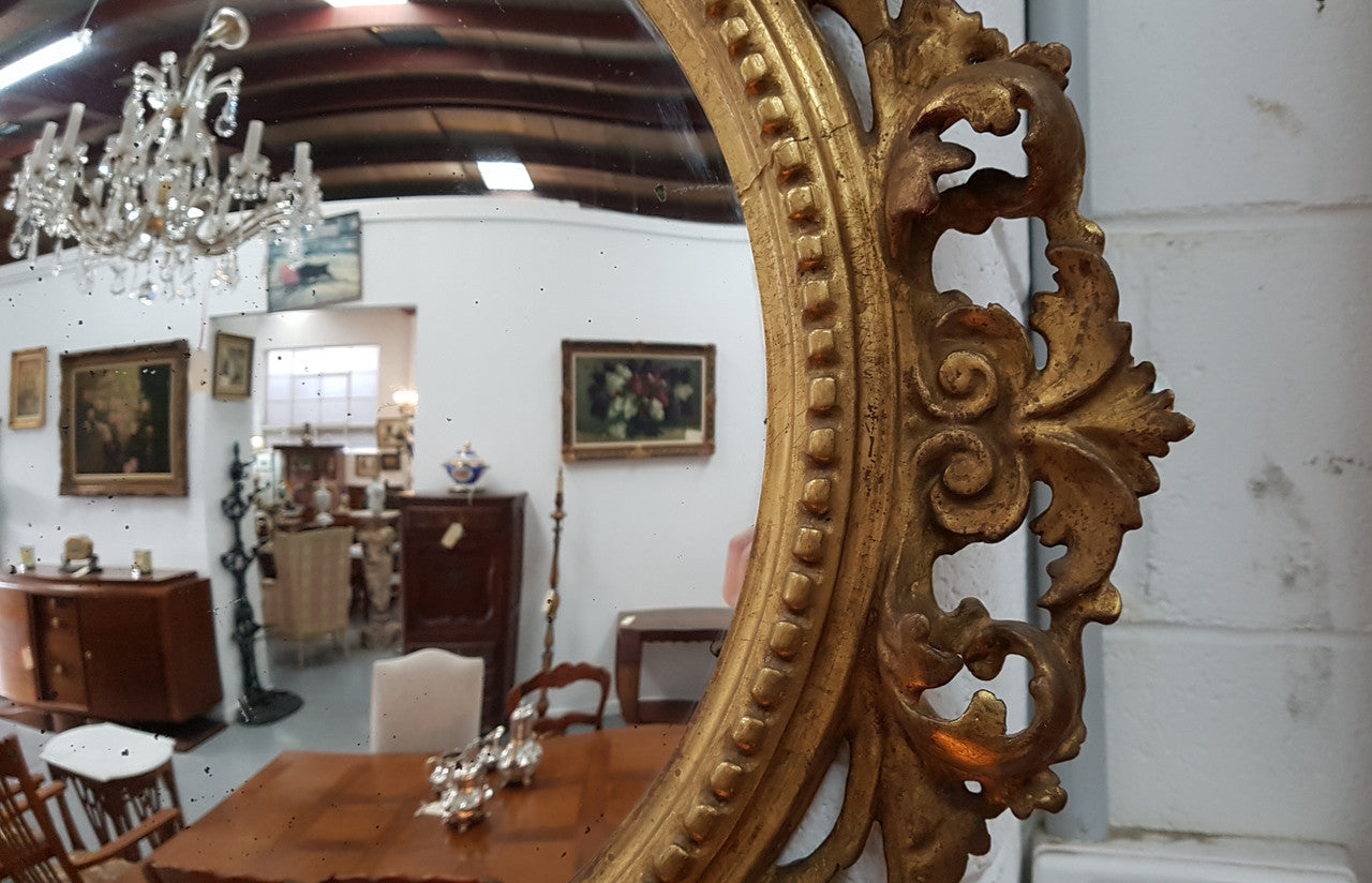 Large round carved wooden convex mirror. Still contains its original mirror which shows signs of aging.