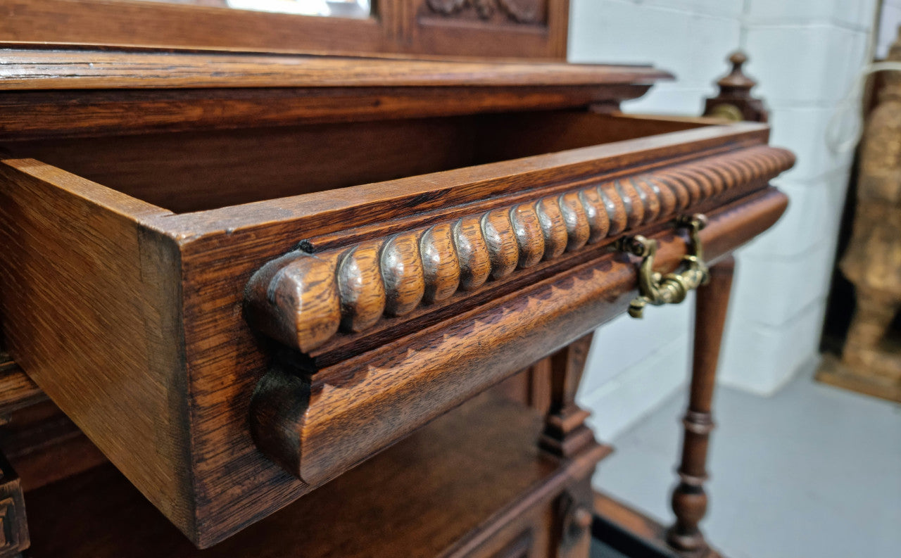 Grand Henry 2nd Style French Oak hall stand with 12 hanging hooks. Also has one cupboard and drawer for storage along with a mirror and two areas either side for umbrellas and walking sticks. In good original detailed condition.